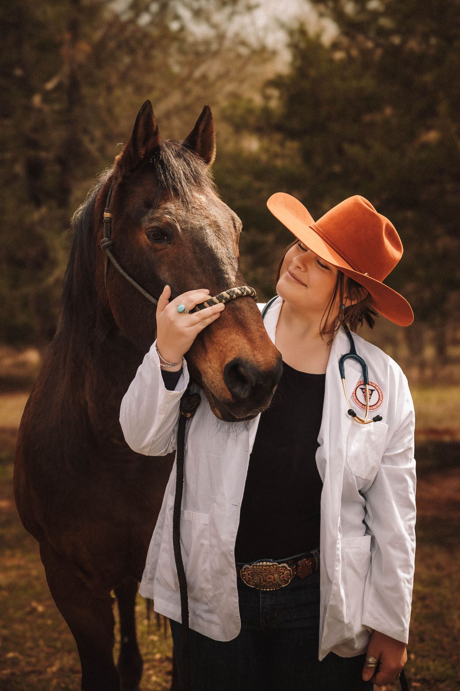 Equine veterinarian in orange hat and white coat examining a dark brown horse in an outdoor autumn setting.