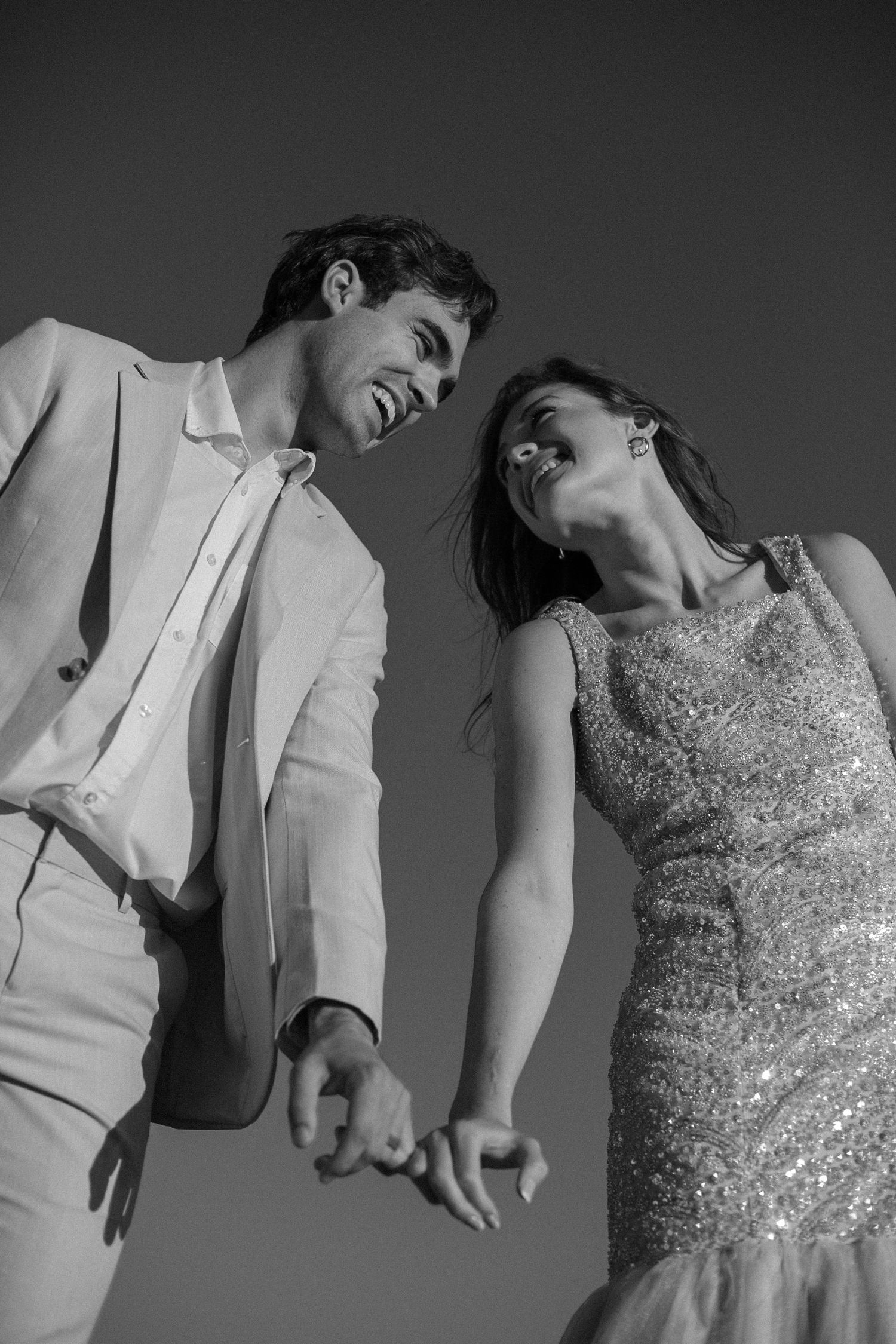 Intimate black and white wedding portrait showing the bride's elegant bow-back dress and the groom's tender embrace