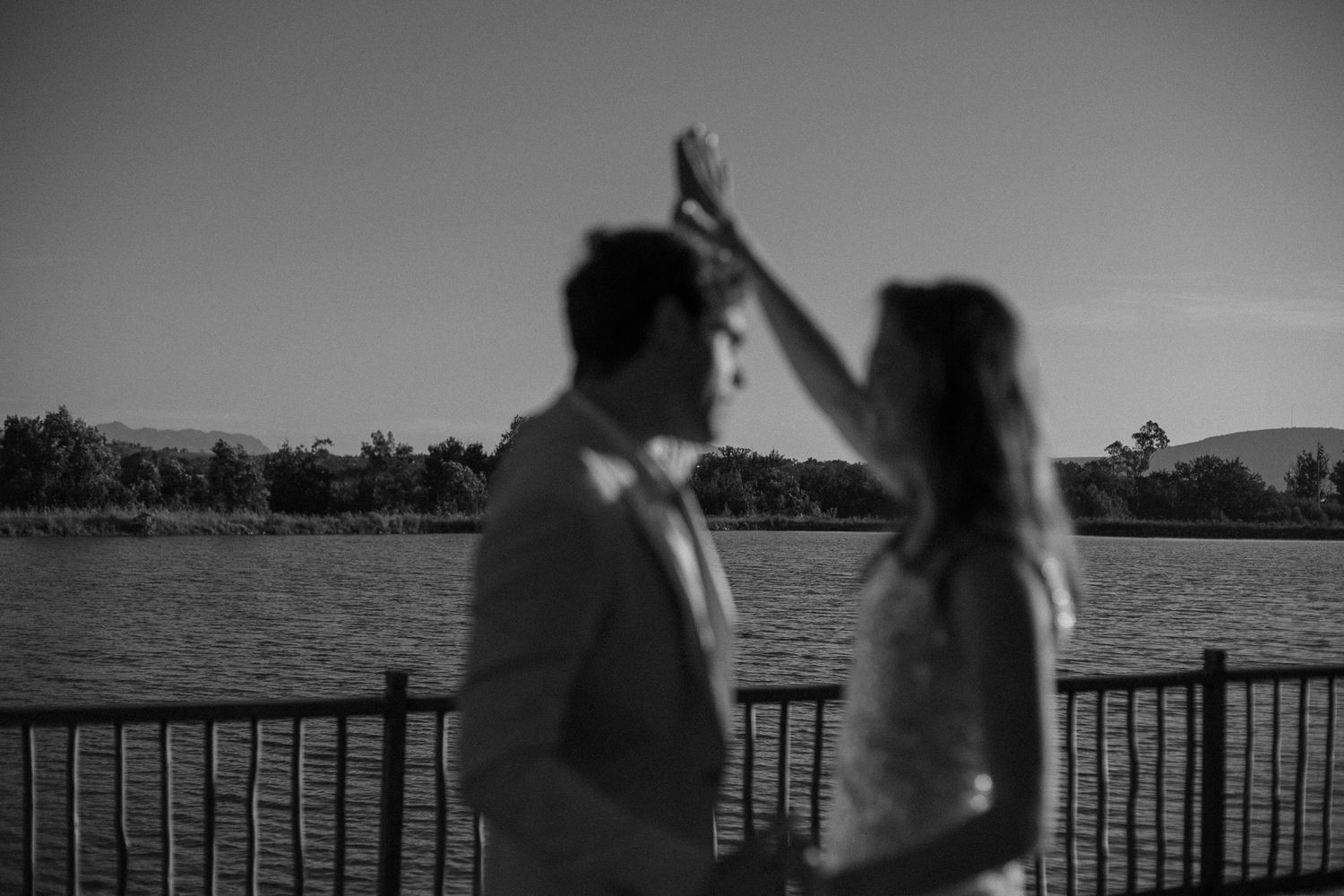A elopement couple out of focus, dancing, water in the background