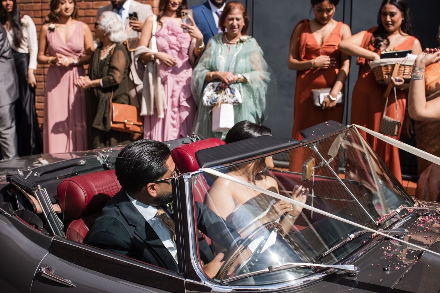 Groom arriving in a convertible car during an Asian wedding celebration