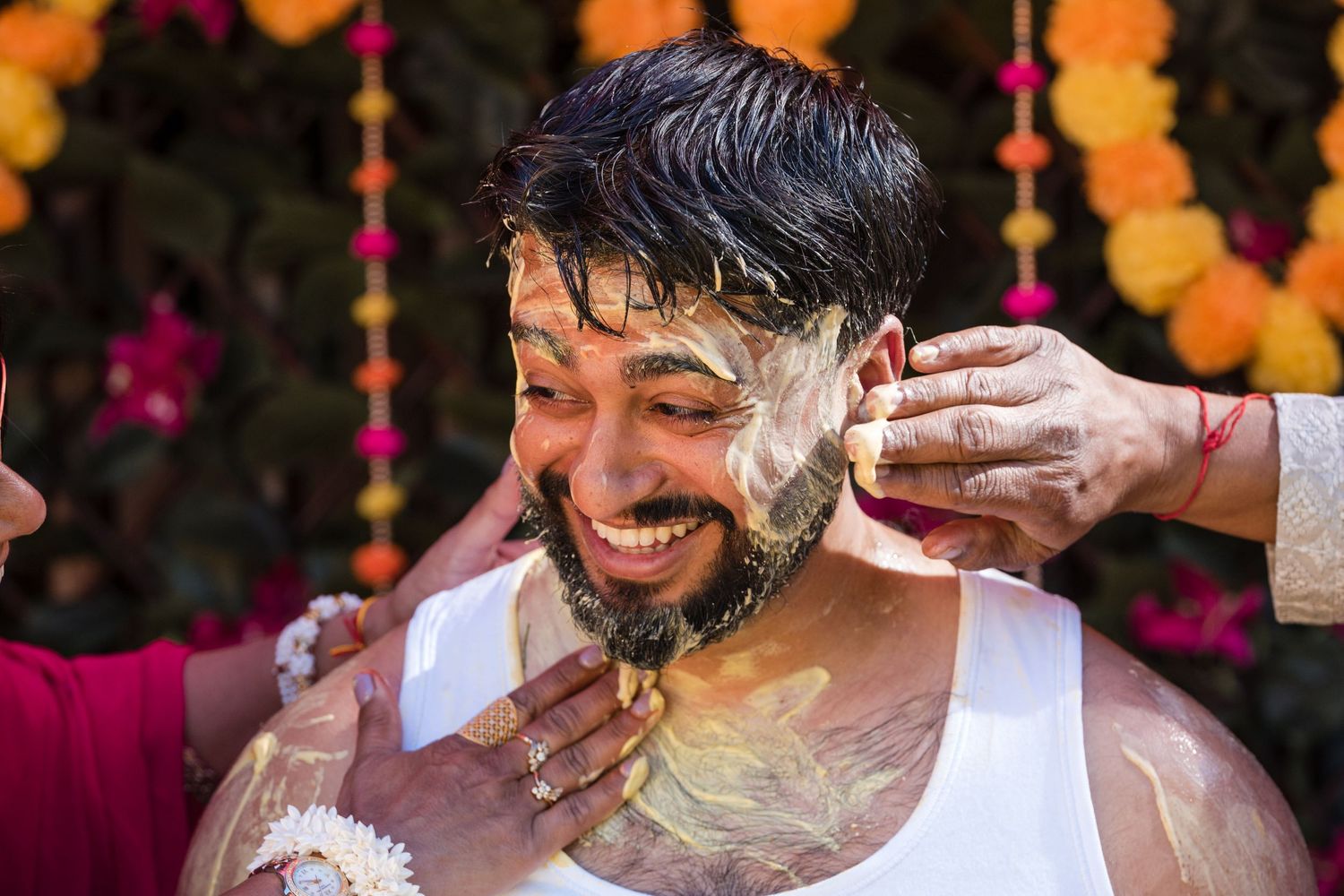 Smiling groom with turmeric haldi paste applied to his face during traditional Indian pre-wedding ceremony.