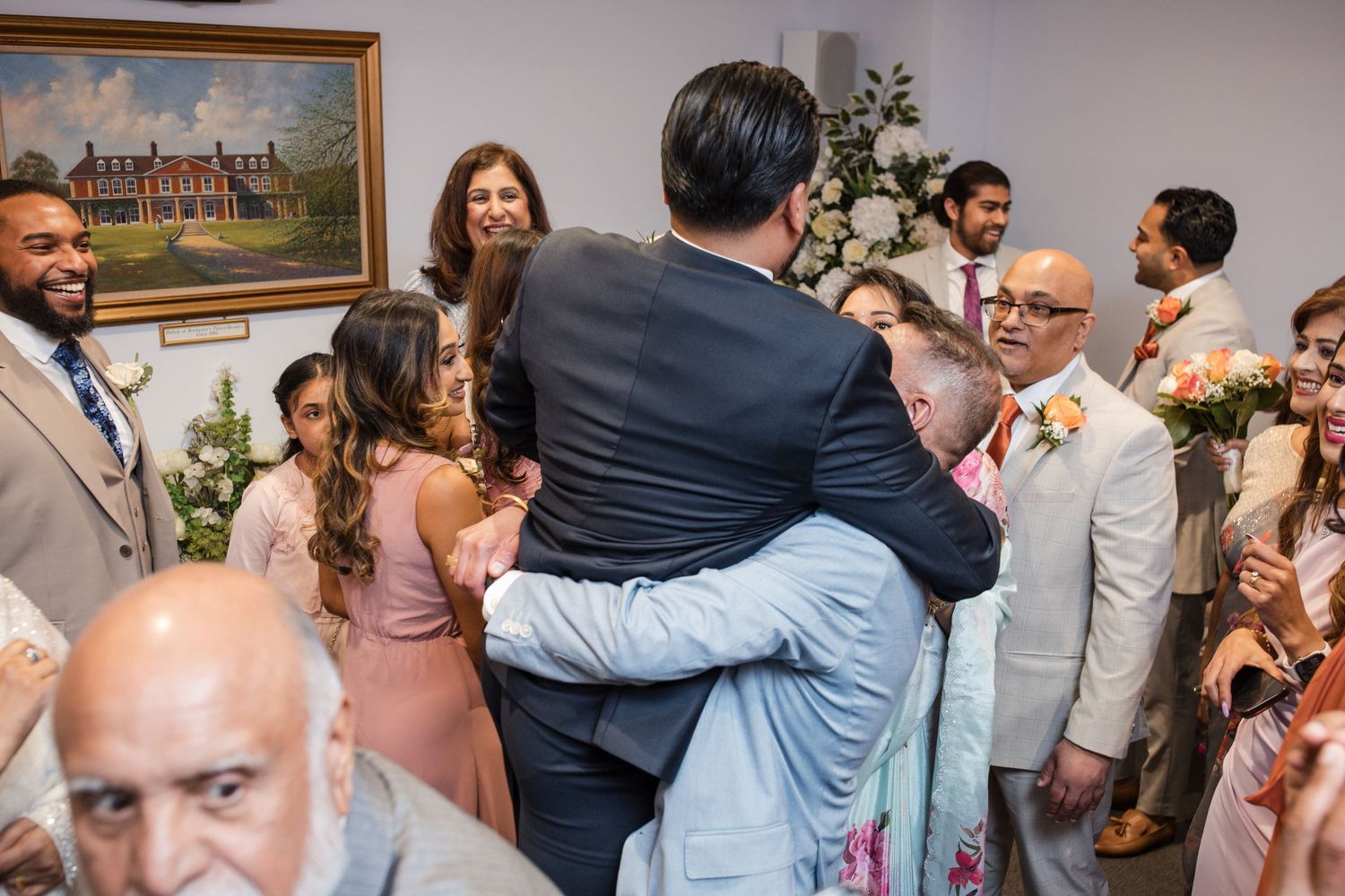 Wedding guests embracing and celebrating after ceremony in decorated reception room.
