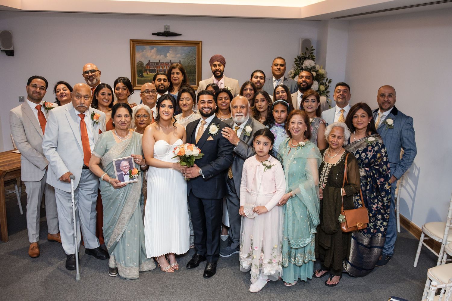 Large family group photo with bride and groom at wedding venue with Christmas tree.