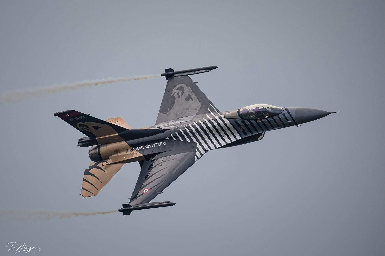 Turkish F-16 Solo Turk display jet in striking metallic livery pulling steep climb with vapor trails.