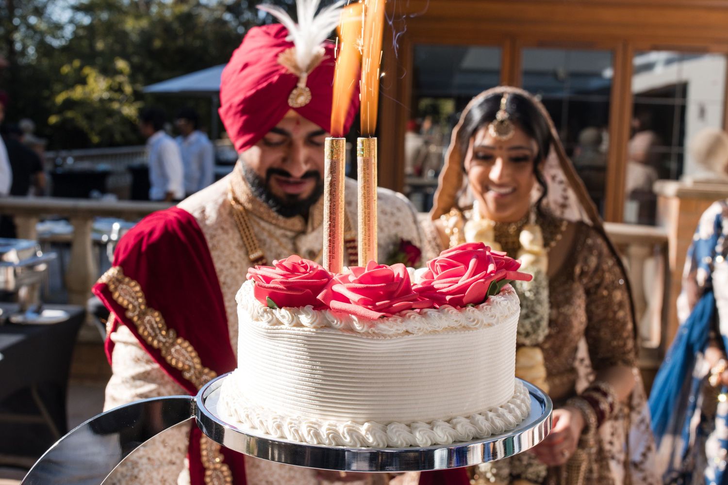 Bride and groom posing behind their wedding cake