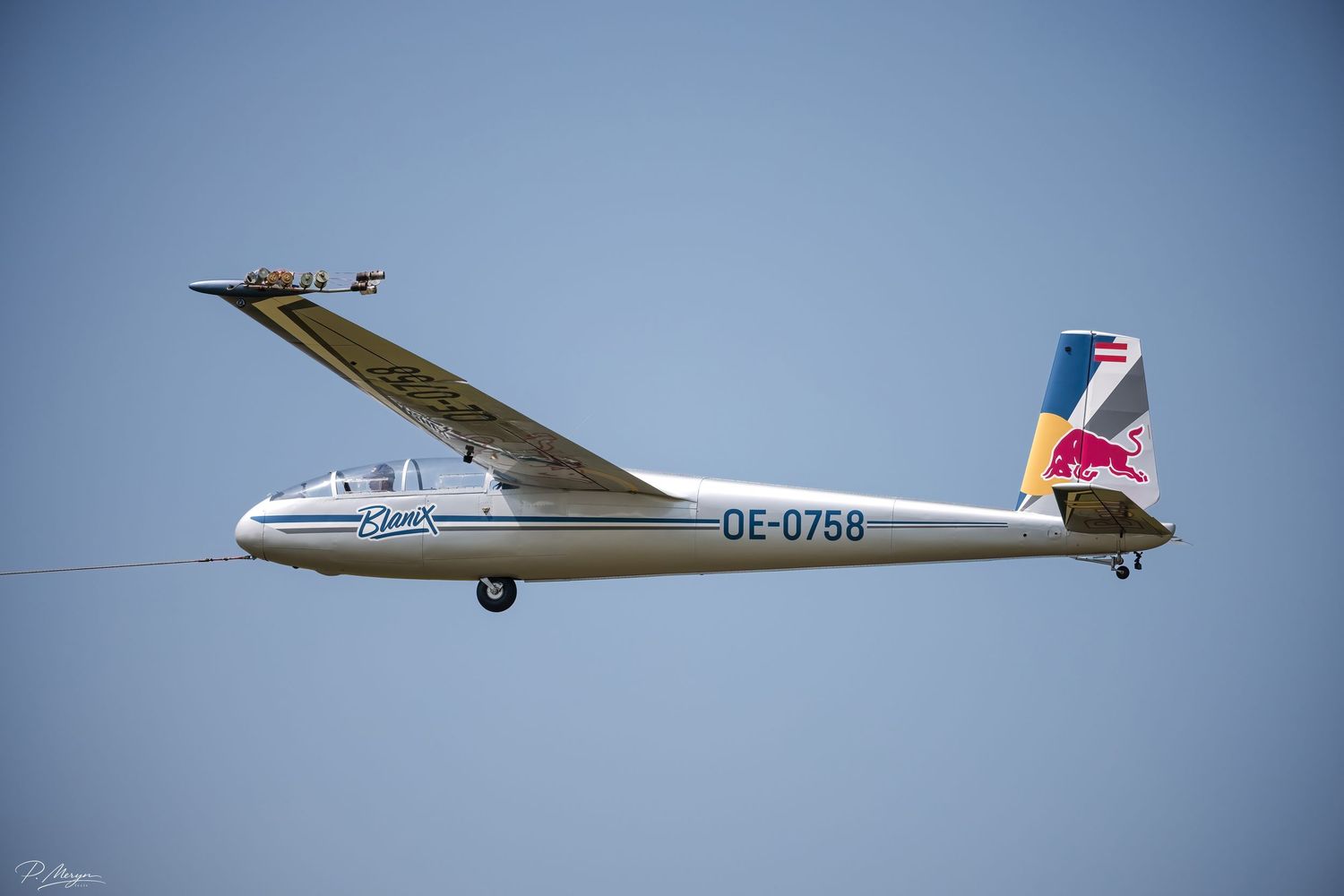Red Bull sponsored glider OE-0758 being towed for launch at an airshow event.
