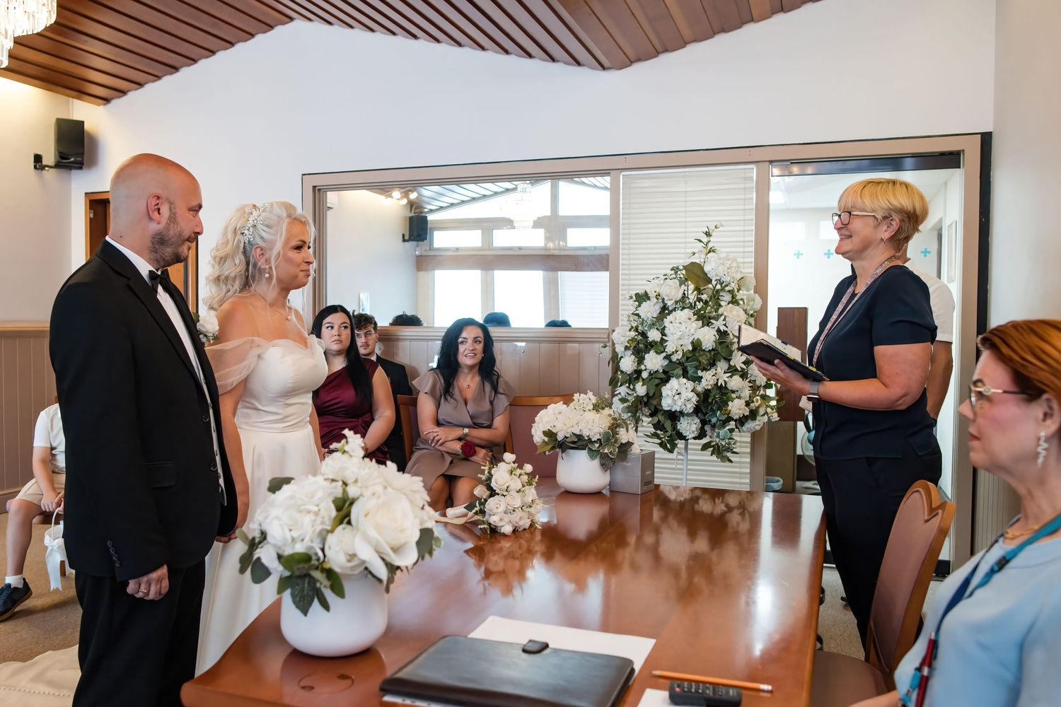 Bride and groom exchange vows before an officiant at an elegant indoor wedding ceremony.
