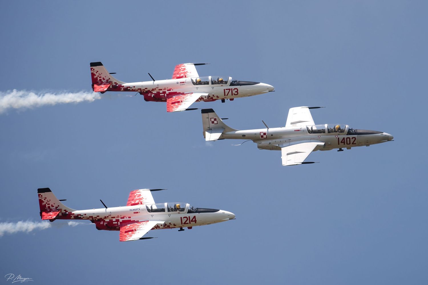 Four Polish Air Force TS-11 Iskra jets in formation with red and white smoke trails.