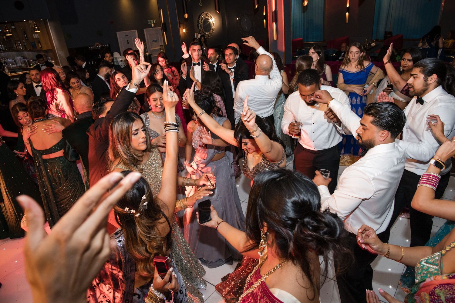 Vibrant Indian wedding reception dance floor filled with guests in colorful traditional attire celebrating joyfully.