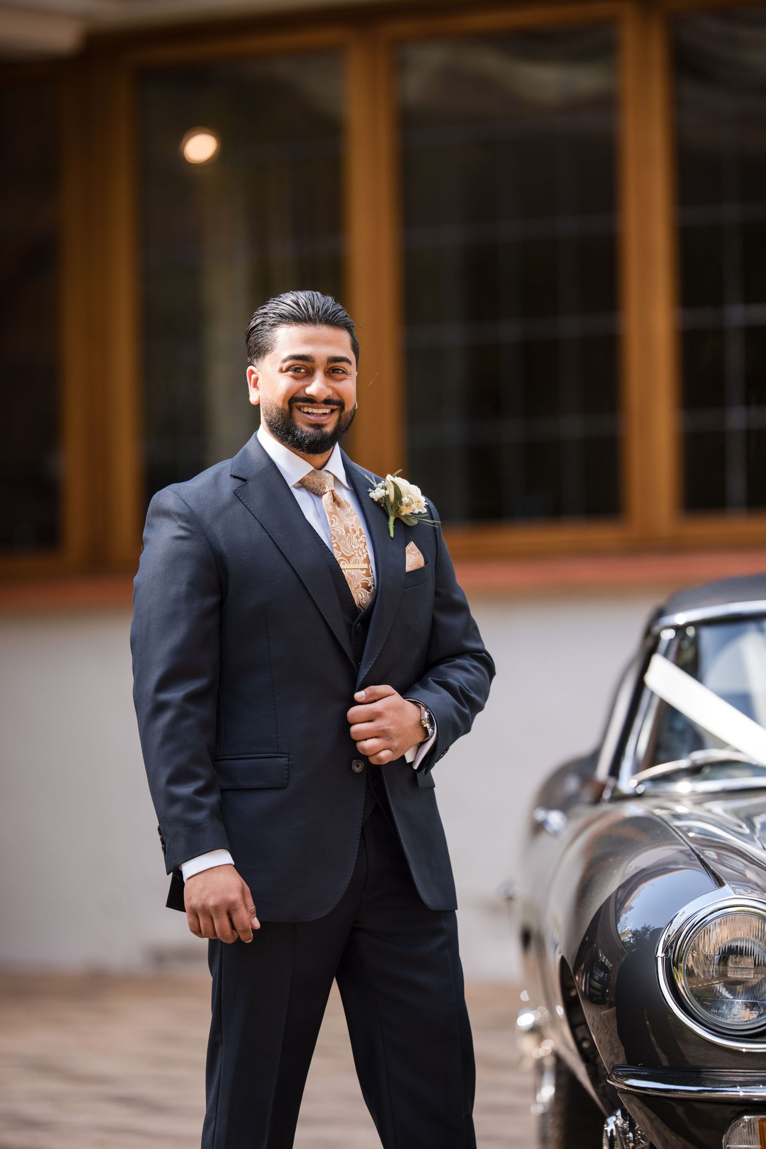 Groom portrait beside a classic wedding car