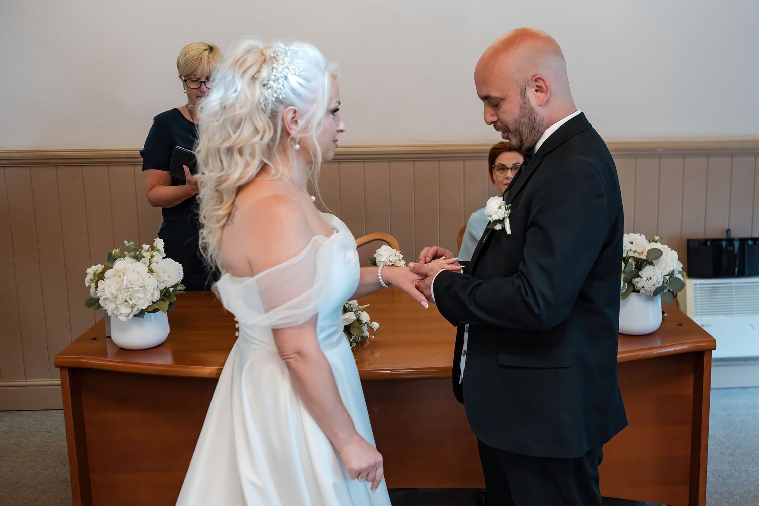 Groom places wedding ring on brides finger during intimate ceremony exchange of vows.