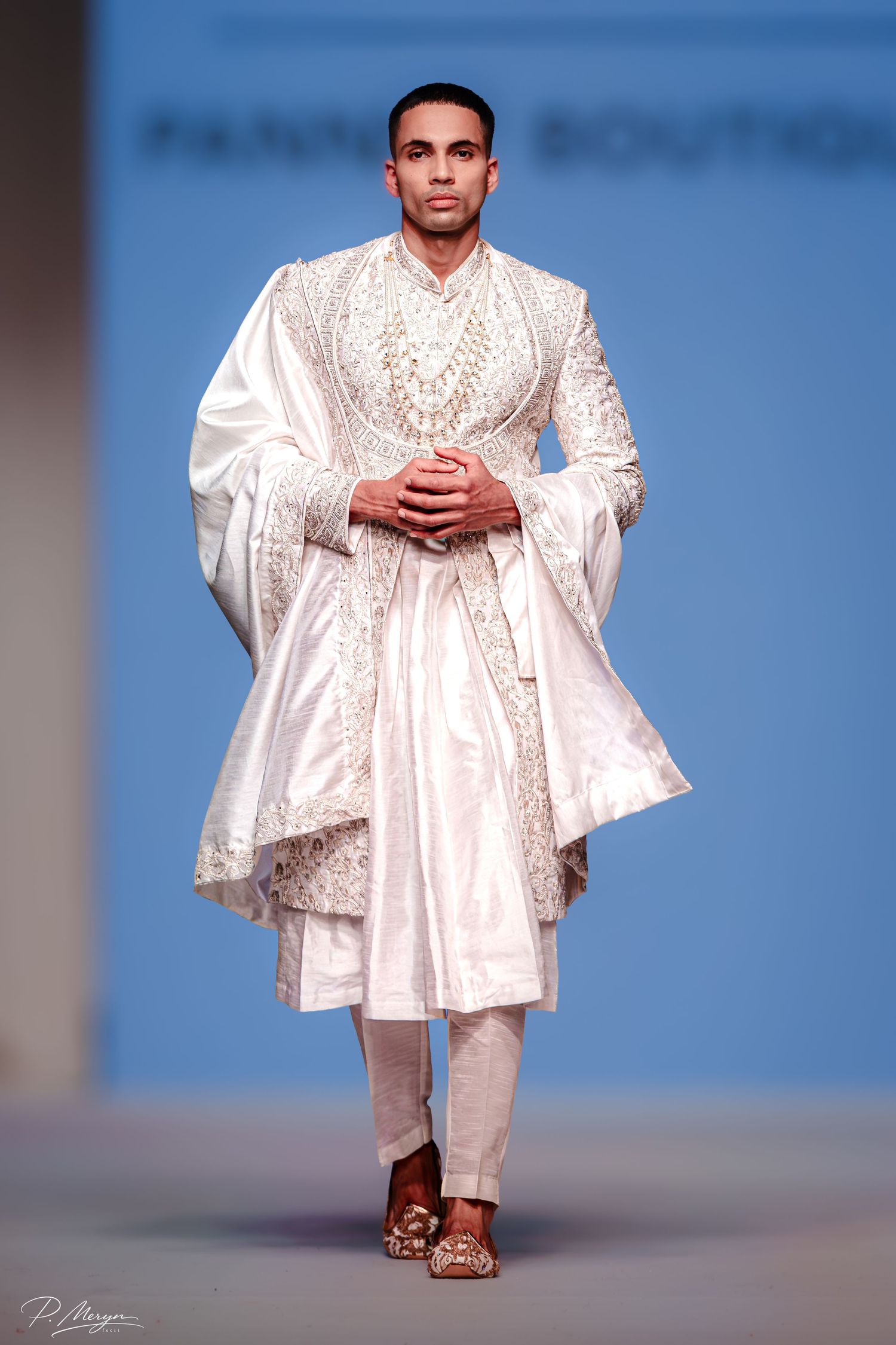 Male model in white embroidered sherwani walks runway at Panthar Boutique fashion show.