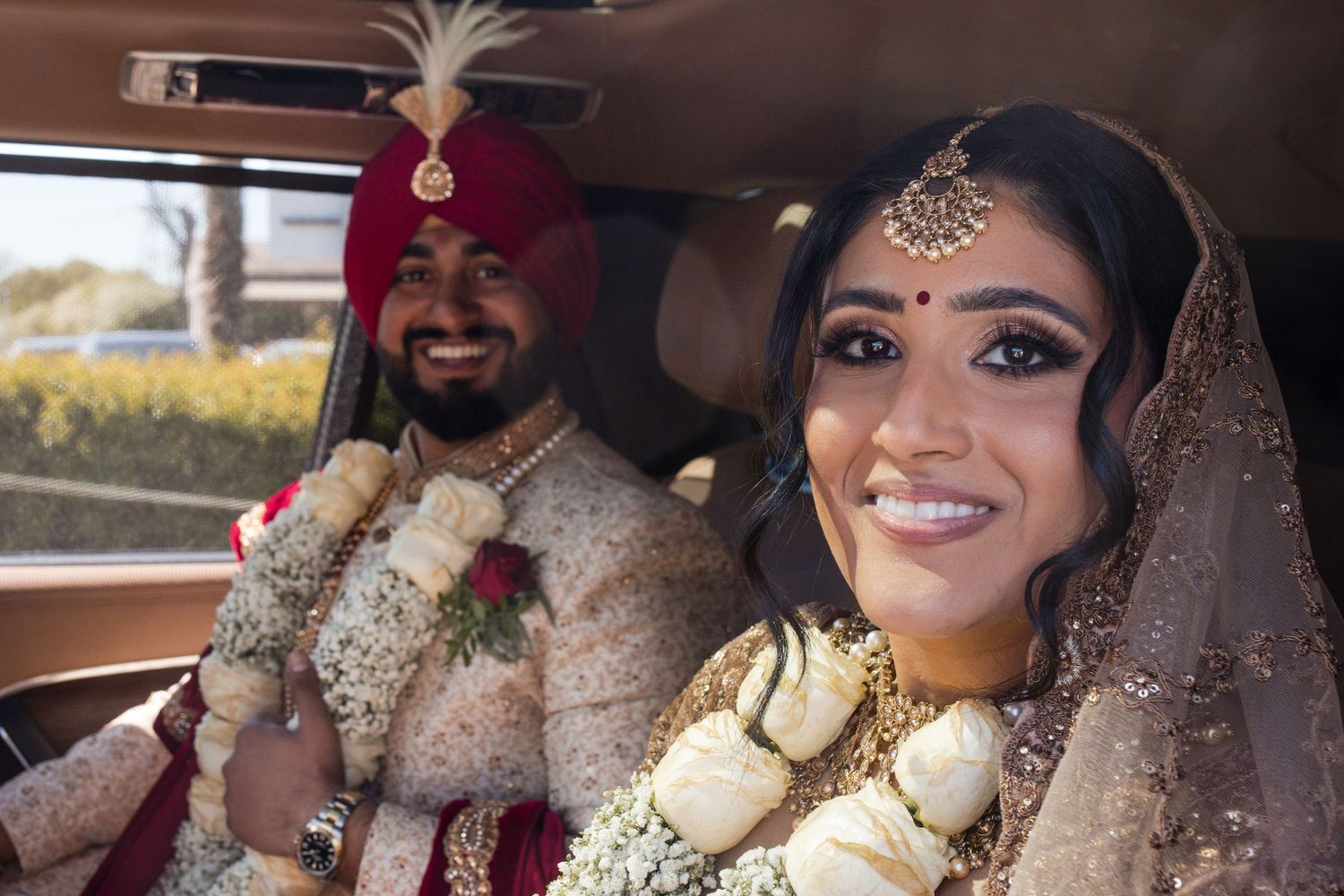 Bride and groom smiling together inside their wedding car