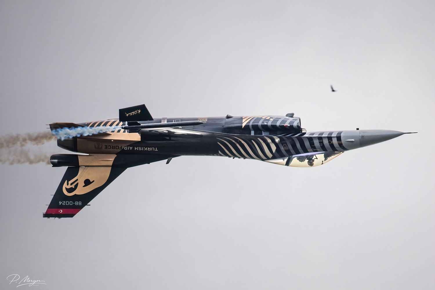Turkish Air Force F-16 Solo Turk jet banking sharply with white smoke trail at airshow.