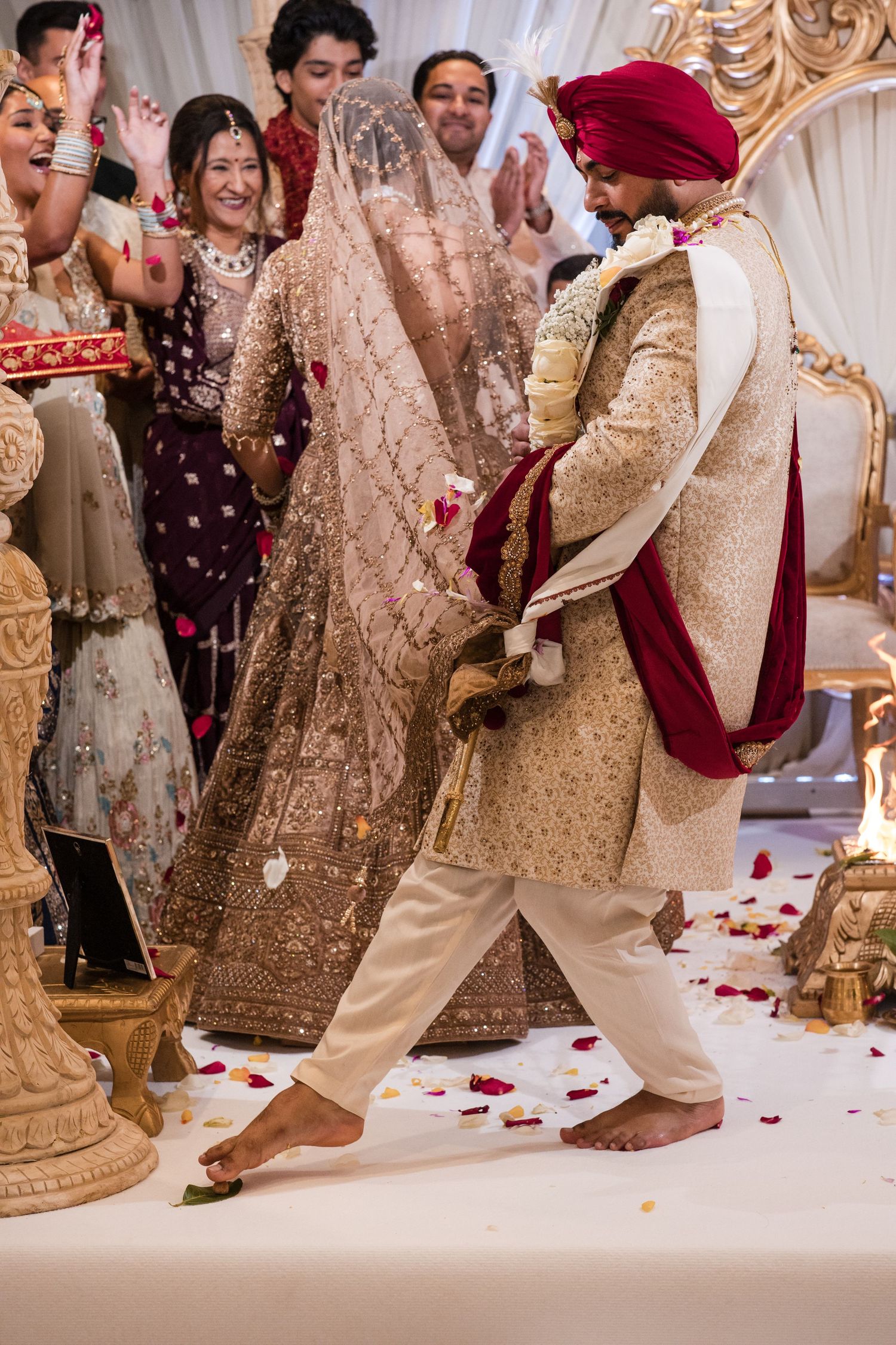 Sikh bride and groom walking ceremonial rounds at Anand Karaj wedding surrounded by joyful guests throwing petals.