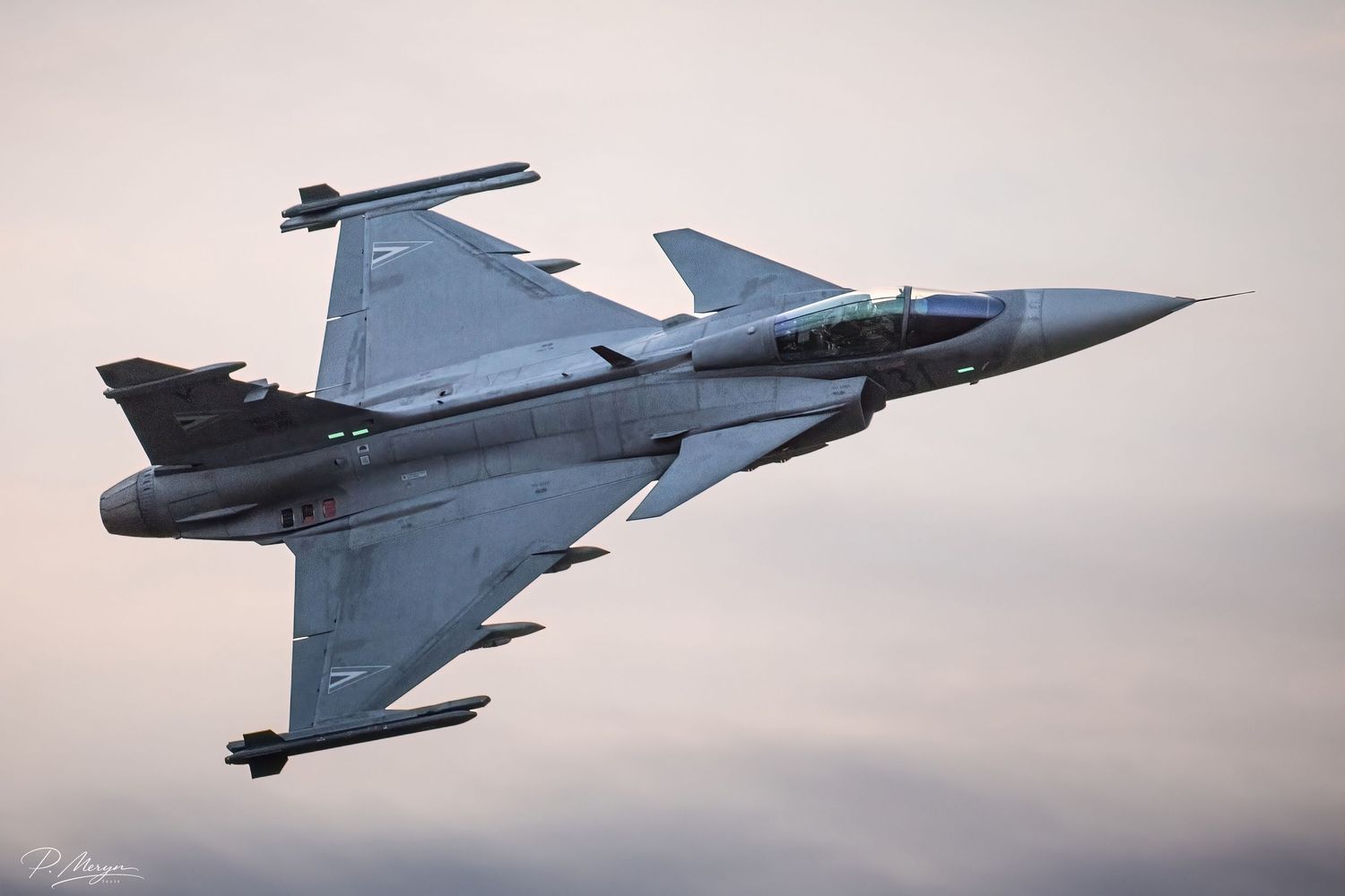Saab Gripen fighter jet banking sharply against dramatic sunset sky during dynamic airshow demonstration.