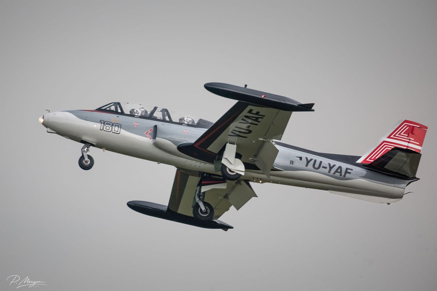 Yugoslav YU-YAF vintage jet trainer aircraft with landing gear down at airshow.