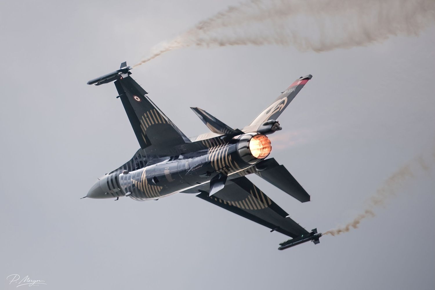 Turkish Air Force F-16 with afterburner and smoke trails during airshow display.