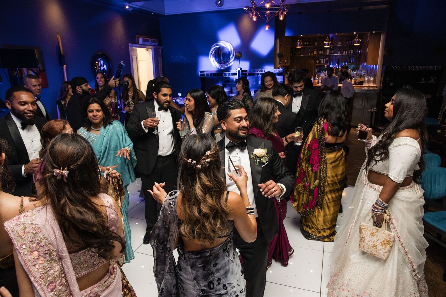 Guests dancing and celebrating on the dance floor at an Indian wedding reception party.