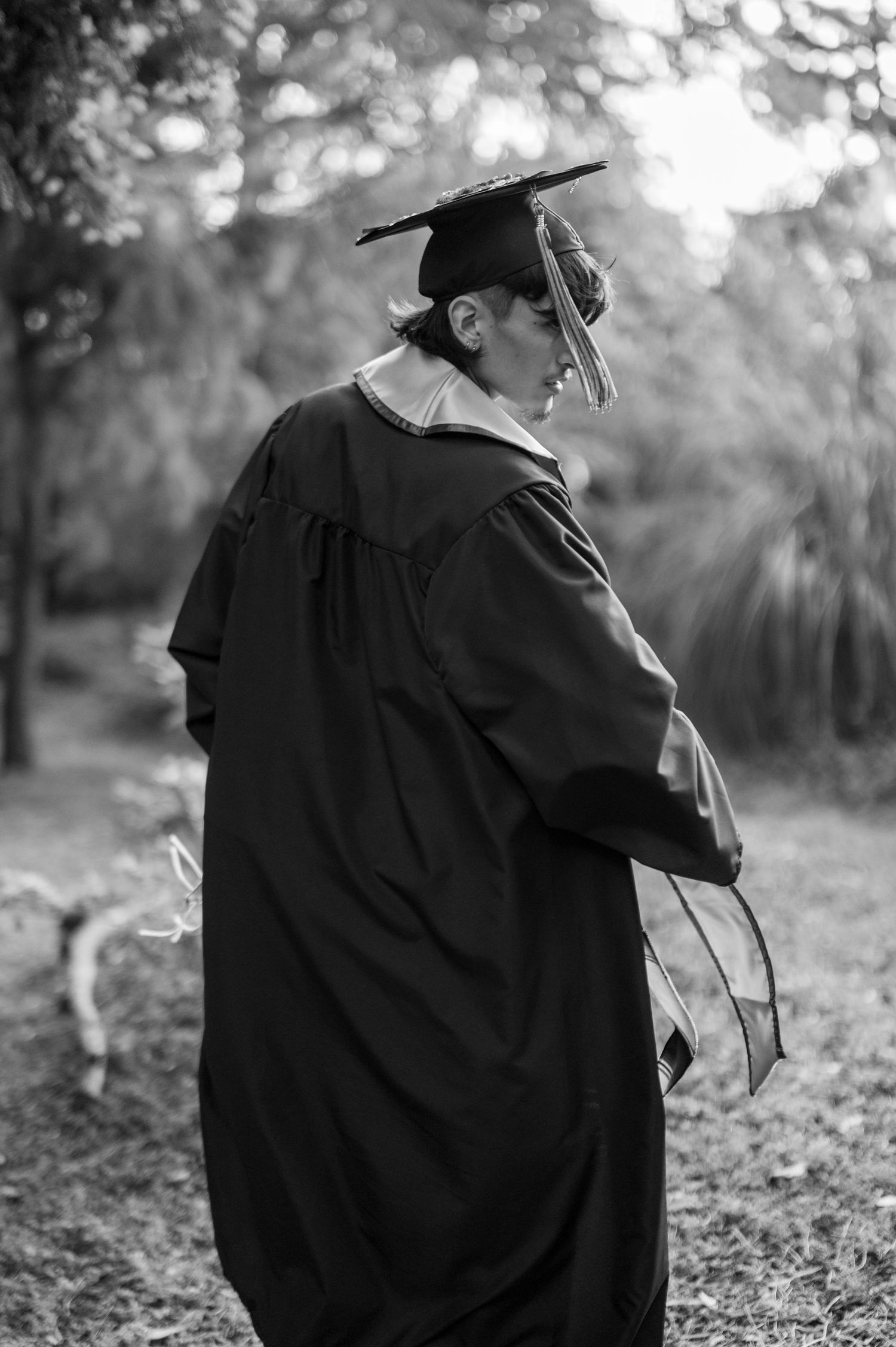 college school graduate in gown and cap walking outdoors, Sacramento State senior graduation portrait in Sacramento by The Padillas