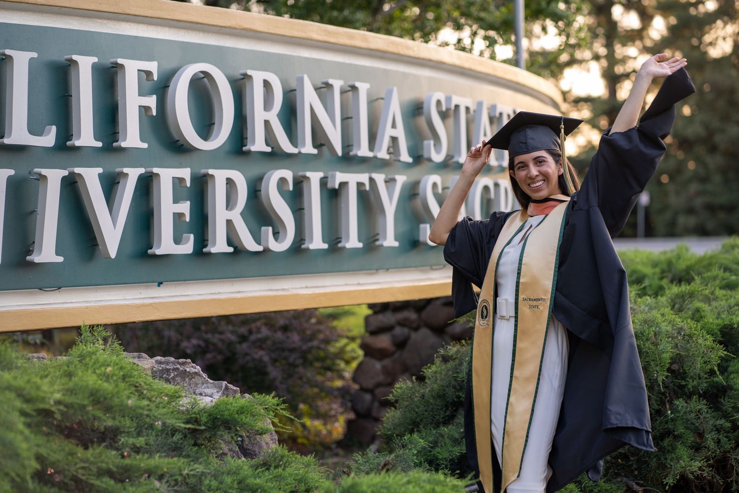 Graduate in cap and gown at Sacramento State University photographed by The Padillas.