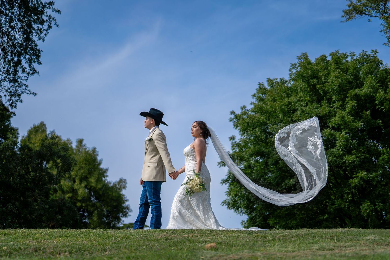 Bride and groom holding hands at UC Davis Arboretum with flowing veil, outdoor Northern California wedding photography by The Padillas