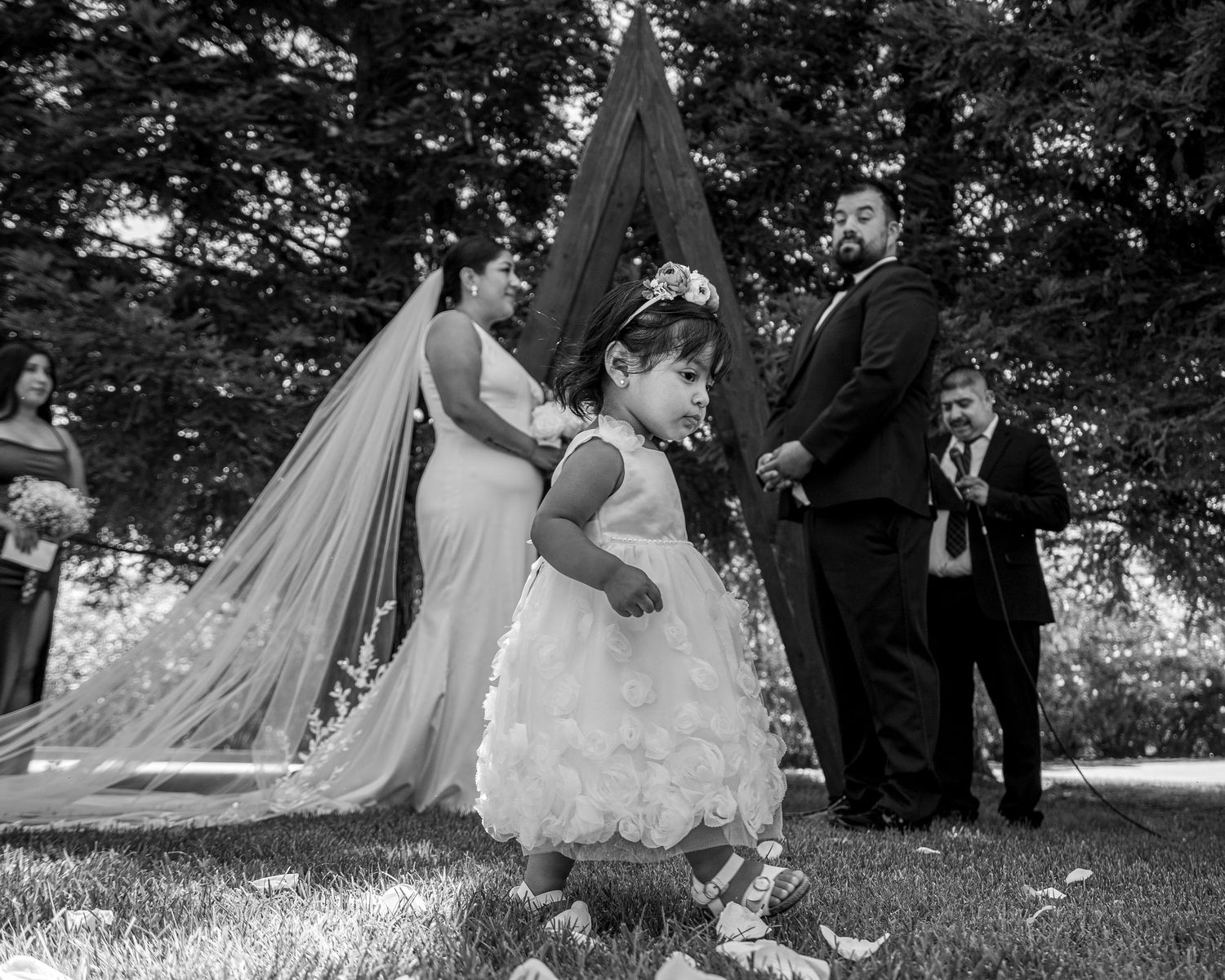 Candid wedding ceremony moment with flower girl walking down aisle, The Ranch at Lone Oak, captured by The Padillas.