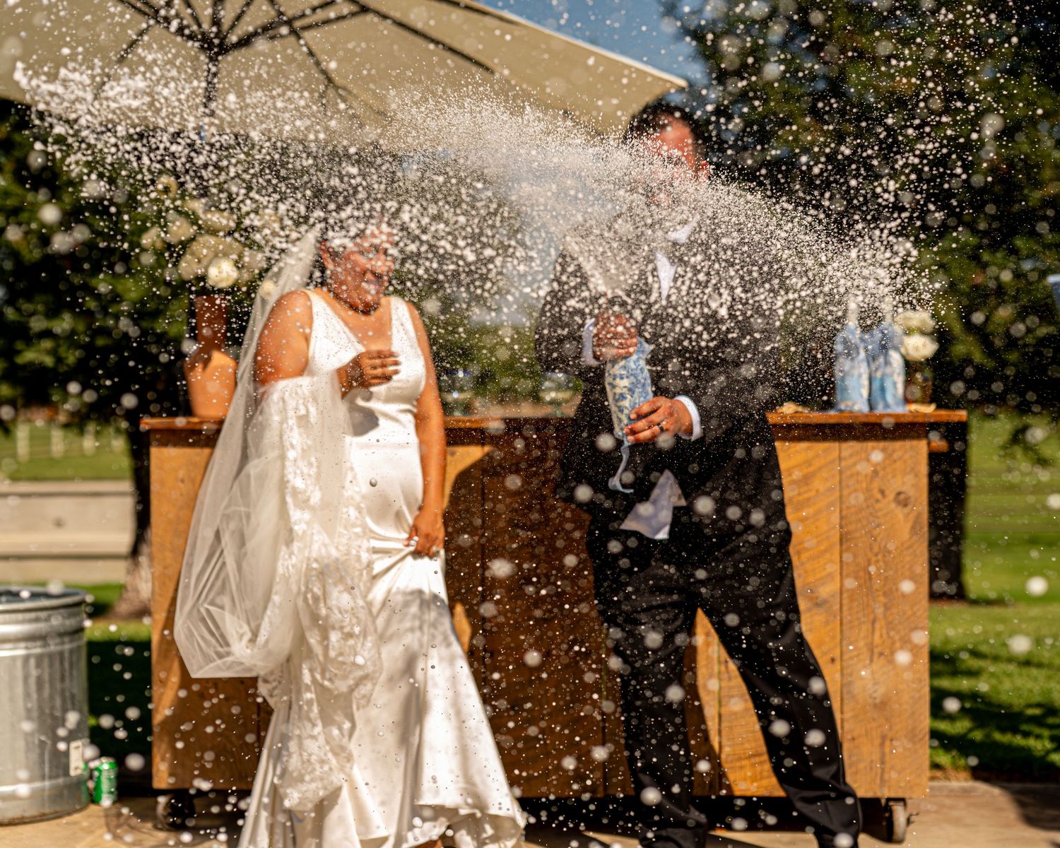 Bride and groom popping champagne at The Ranch at Lone Oak reception, fun wedding celebration moment by The Padillas Sacramento photography