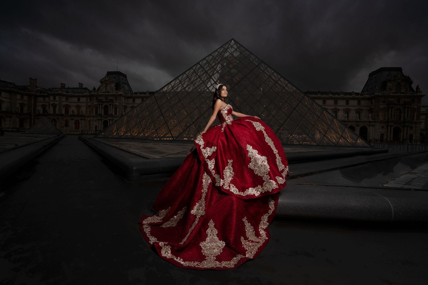 Quinceañera in red gown posing in front of Louvre Pyramid, luxury Paris destination quinceañera photography by The Padillas