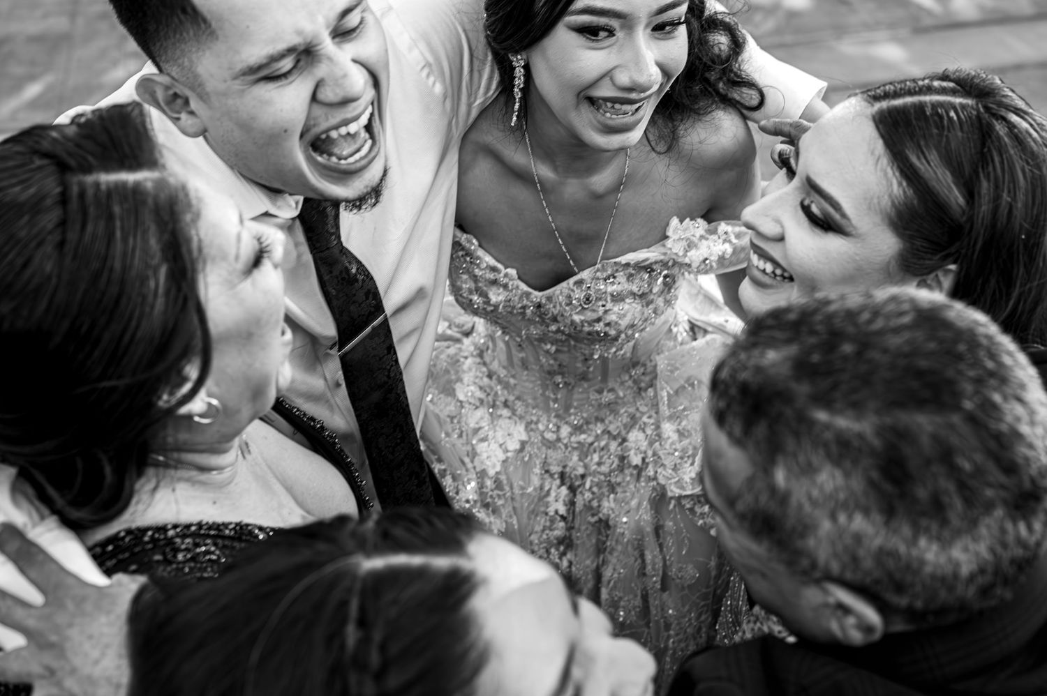 Emotional quinceañera family hug, black & white documentary moment by The Padillas, event day photography.