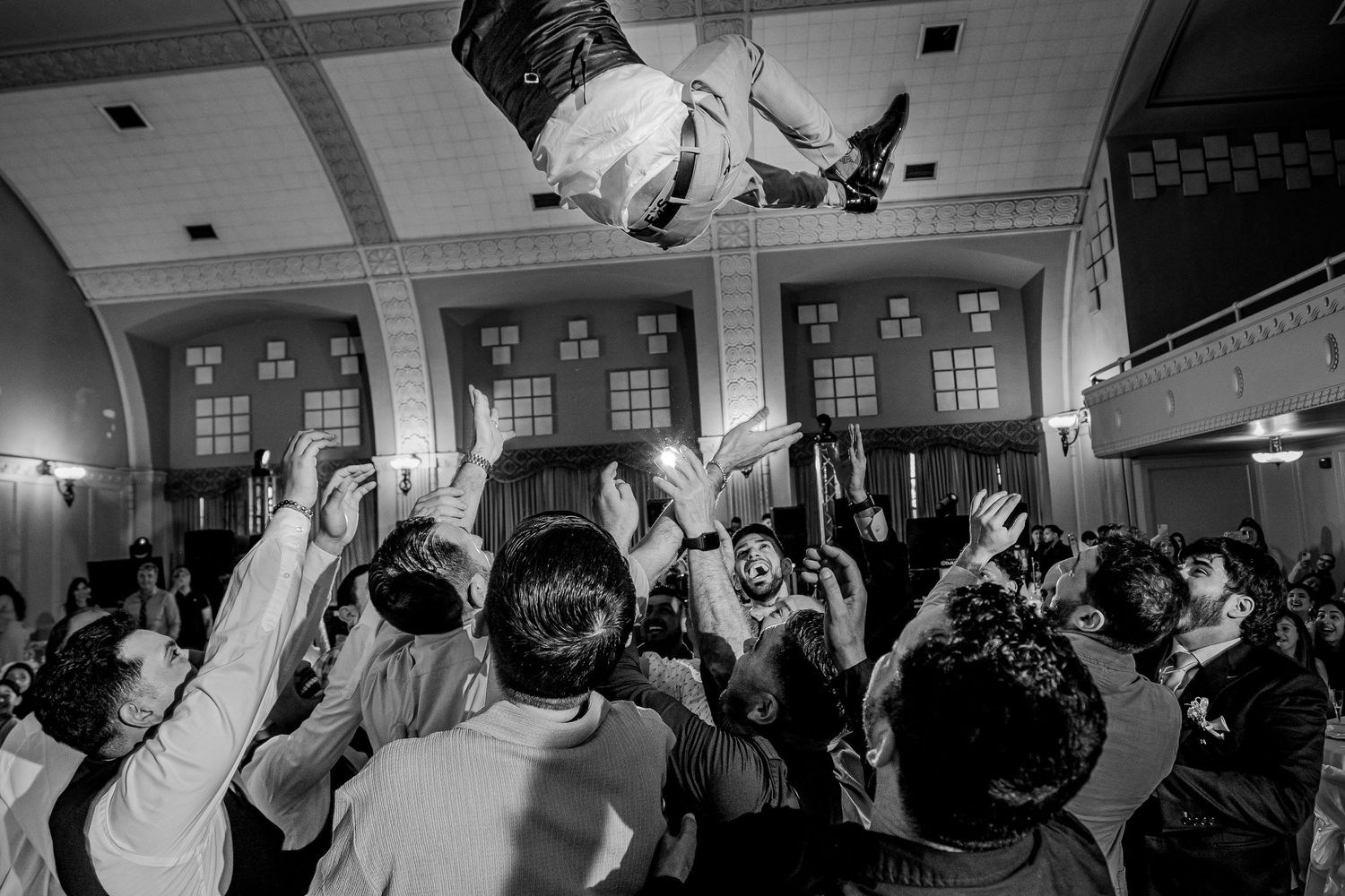 Groomsmen tossing groom into air at lively Mexican wedding reception in Sacramento captured by The Padillas.