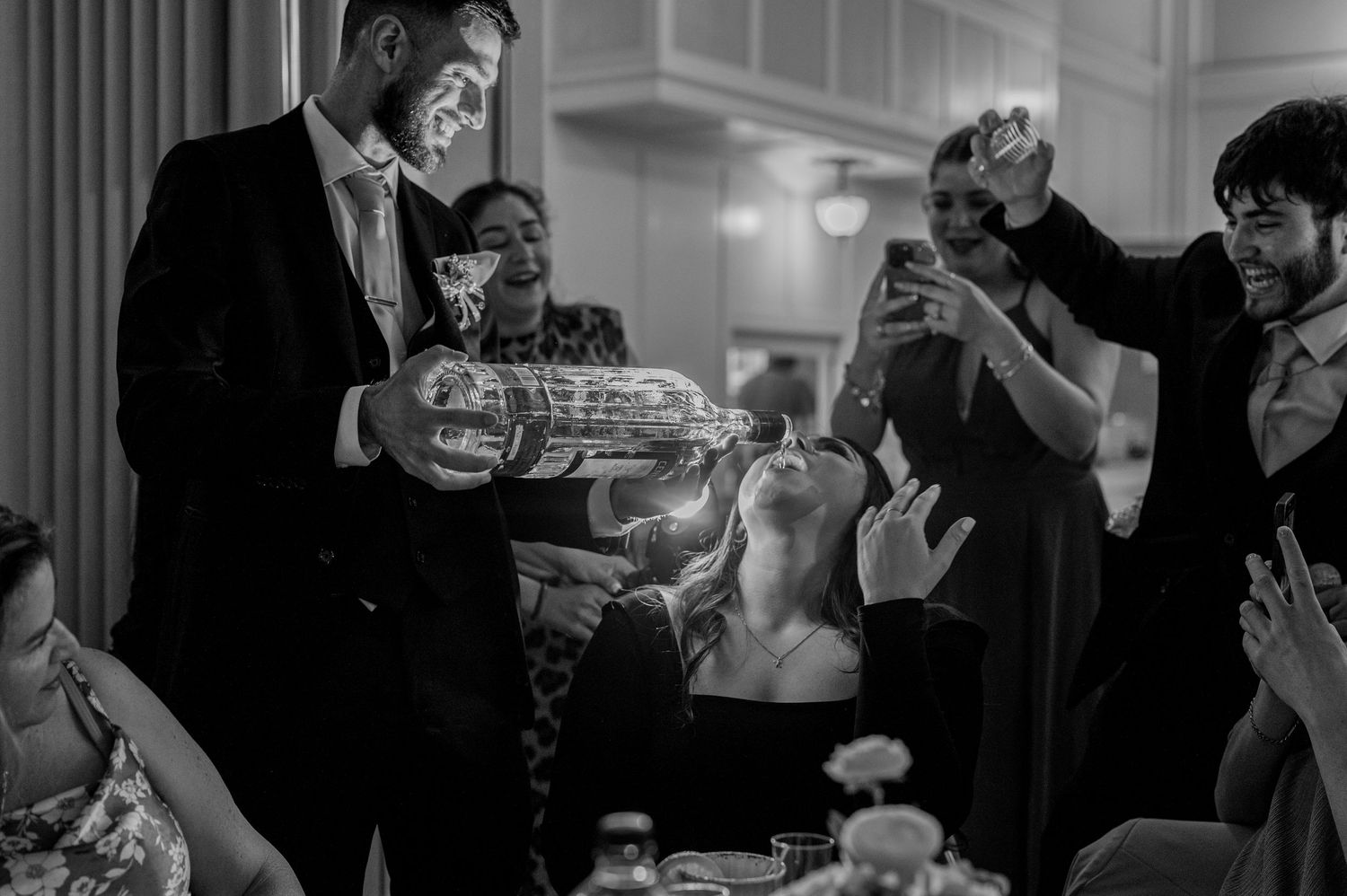 Bride taking tequila shot poured by groom at Sacramento Mexican wedding reception, fun wedding party photo by The Padillas.