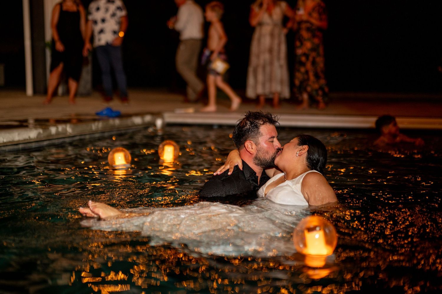 Bride and groom in wedding dress and suit share a romantic kiss in the pool at The Ranch at Lone Oak, documentary wedding photography by The