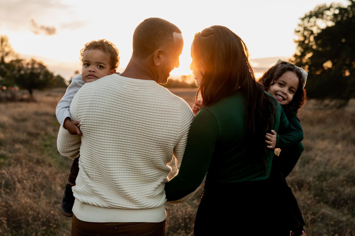 Family session at golden hour in Folsom with parents and kids smiling. Natural light candid moment
