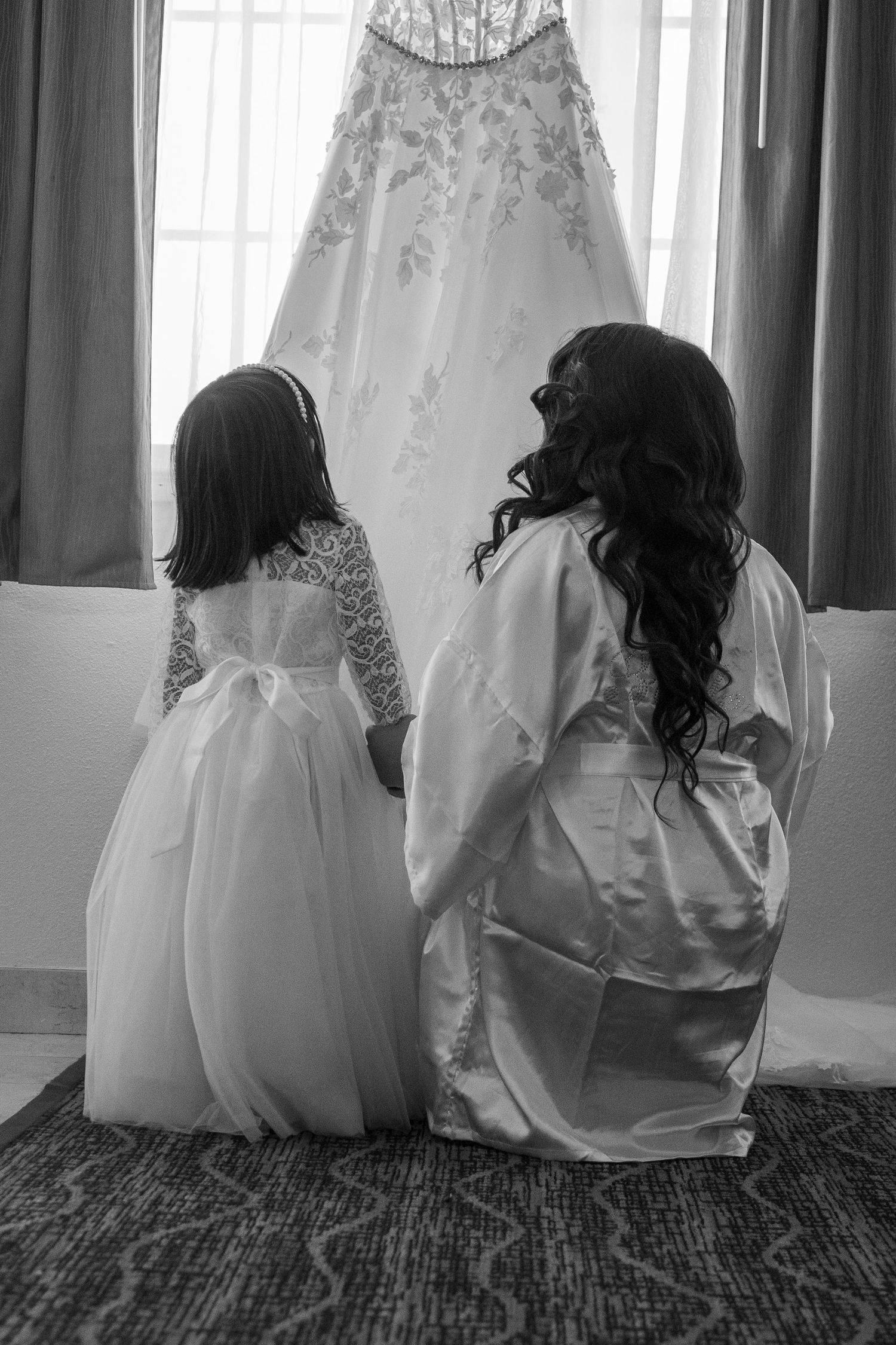 Bride and flower girl admiring wedding dress in Sacramento hotel, emotional pre-ceremony moment, The Padillas Photography.