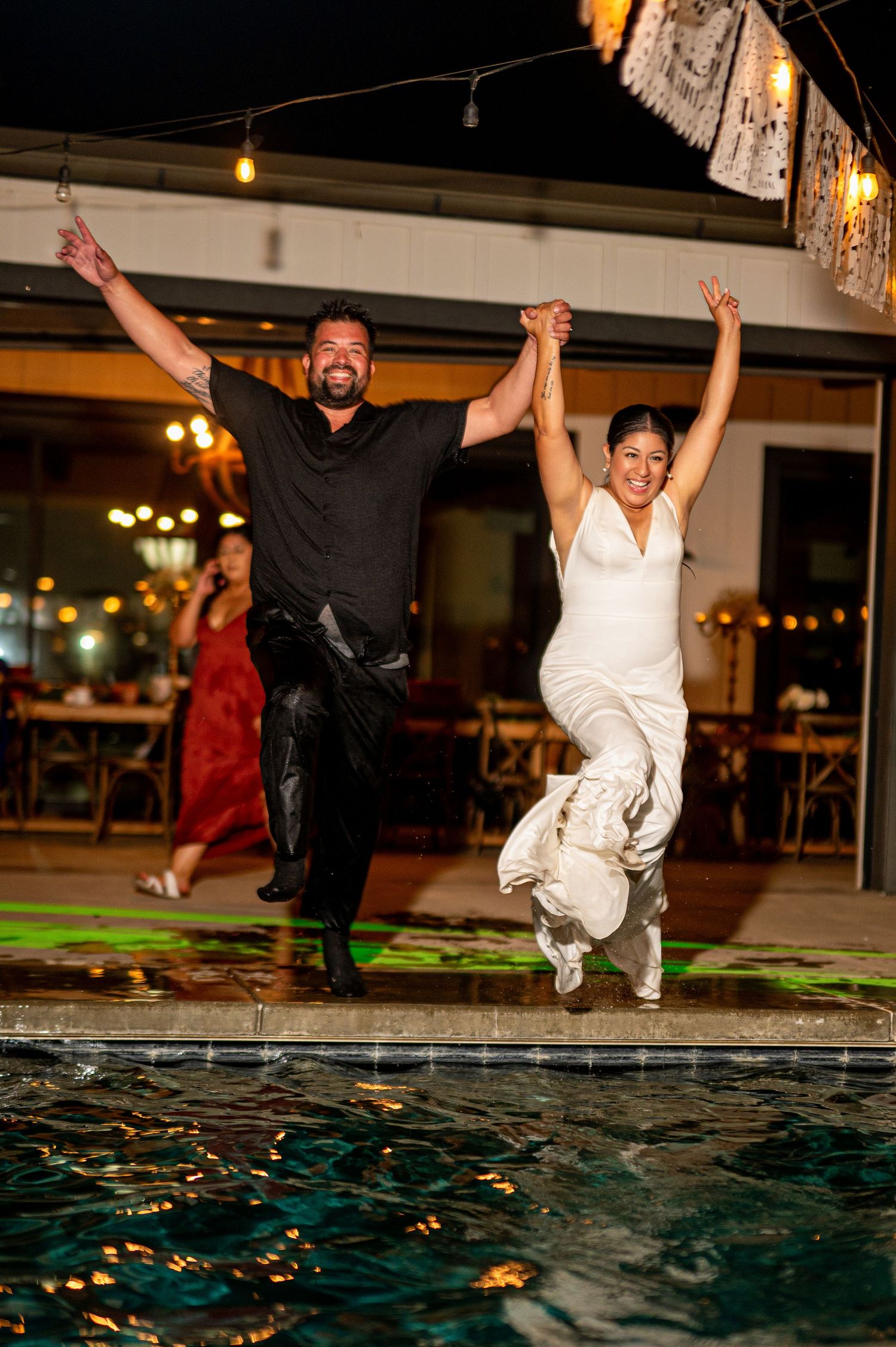 Bride and groom jumping into pool at The Ranch at Lone Oak, fun wedding reception moment captured by The Padillas.