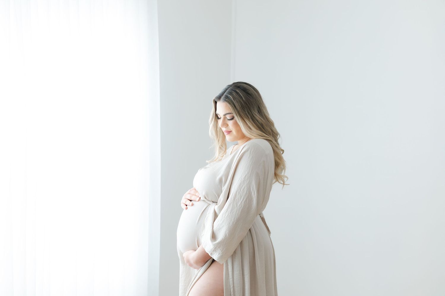 Pregnancy portrait session in a Hendersonville NC studio with neutral tones and soft natural light.