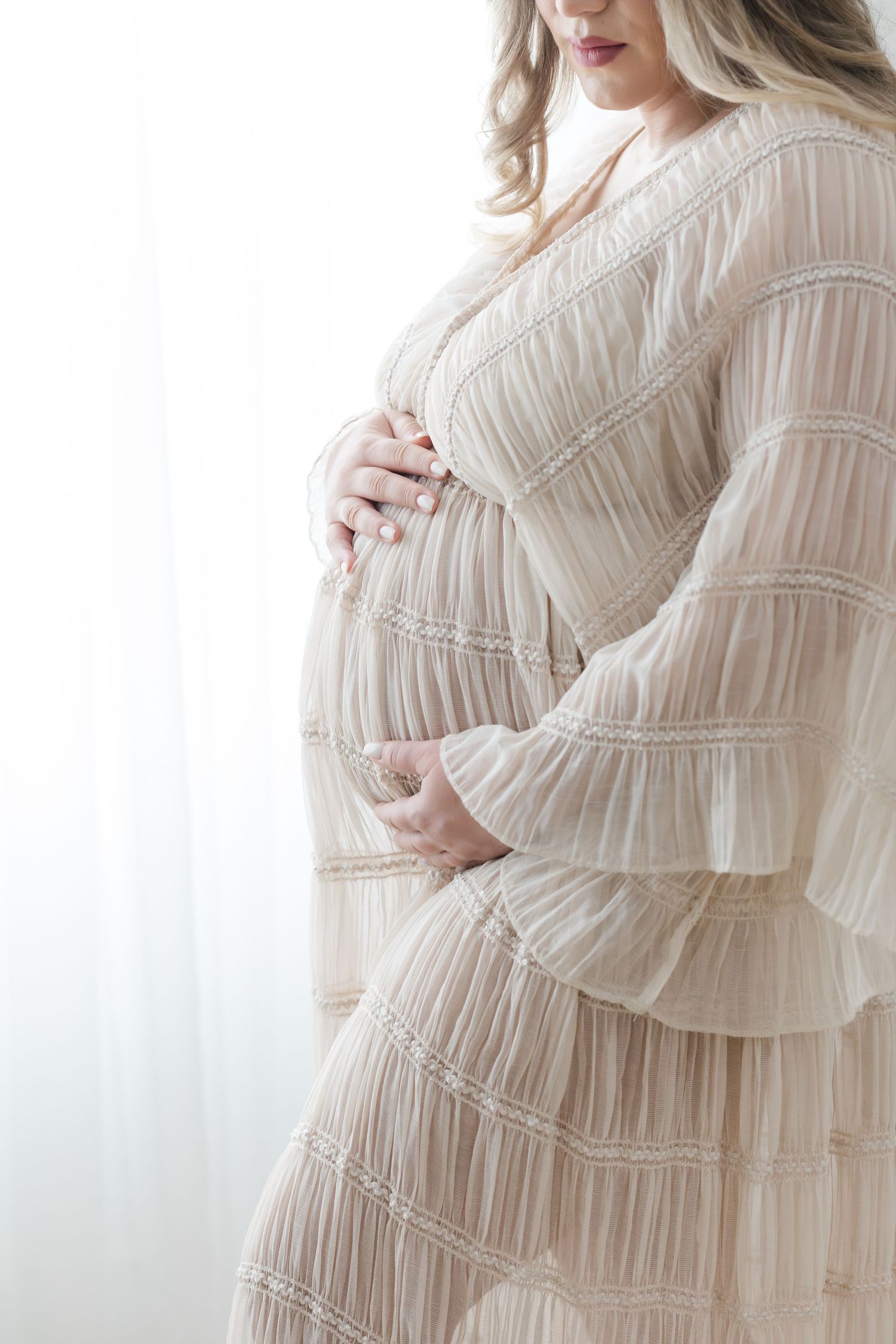 Pregnancy portrait session in a Hendersonville NC studio with neutral tones and soft natural light.