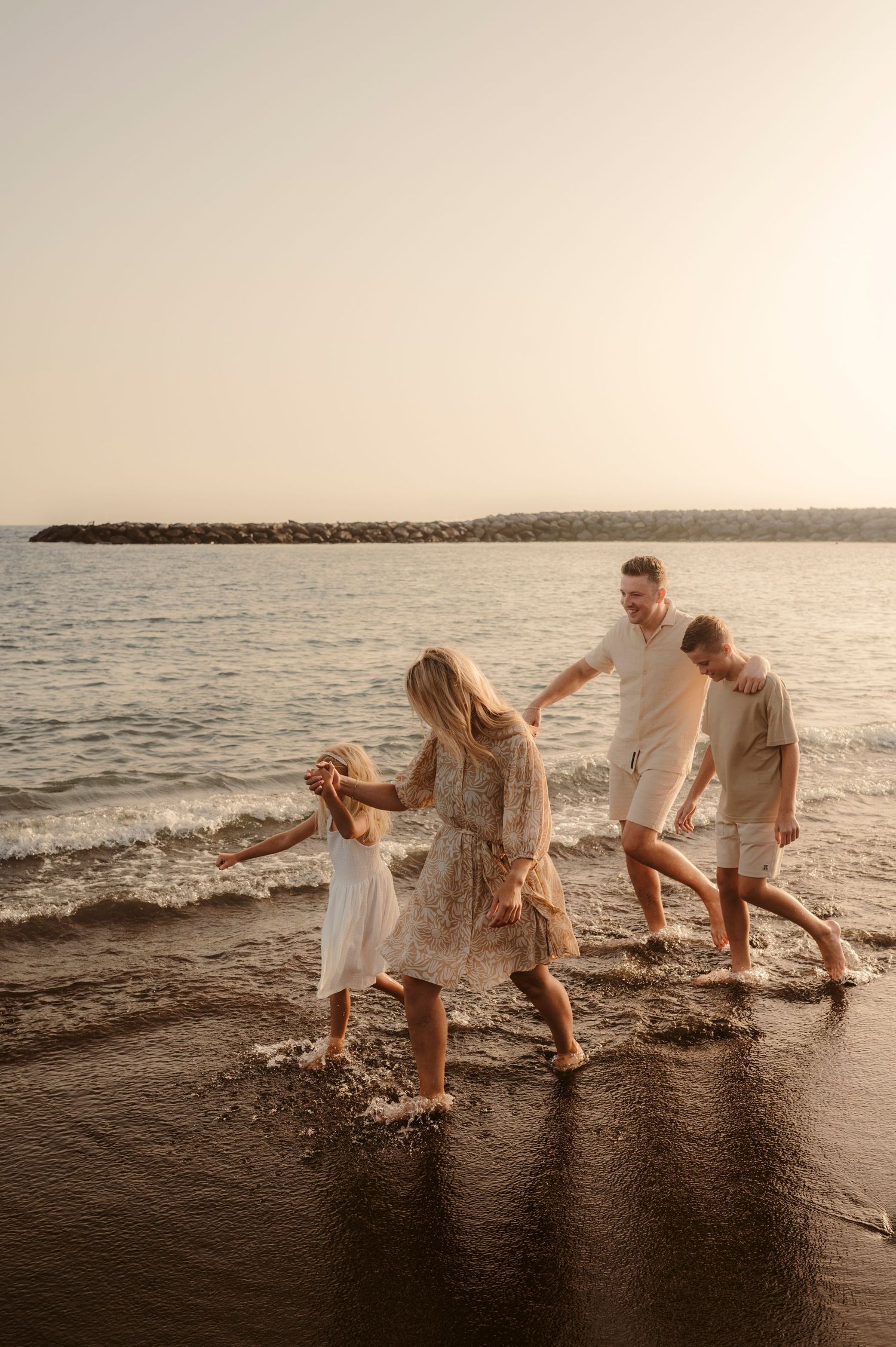 Family moment on beach enjoying waves and sunset, Playa del Duque