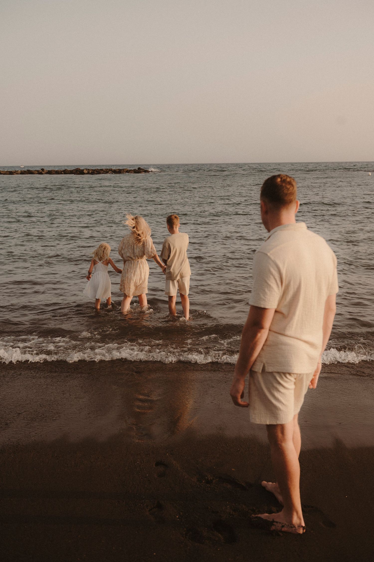 ather watching his family play in ocean at sunset during photoshoot, Playa del Duque