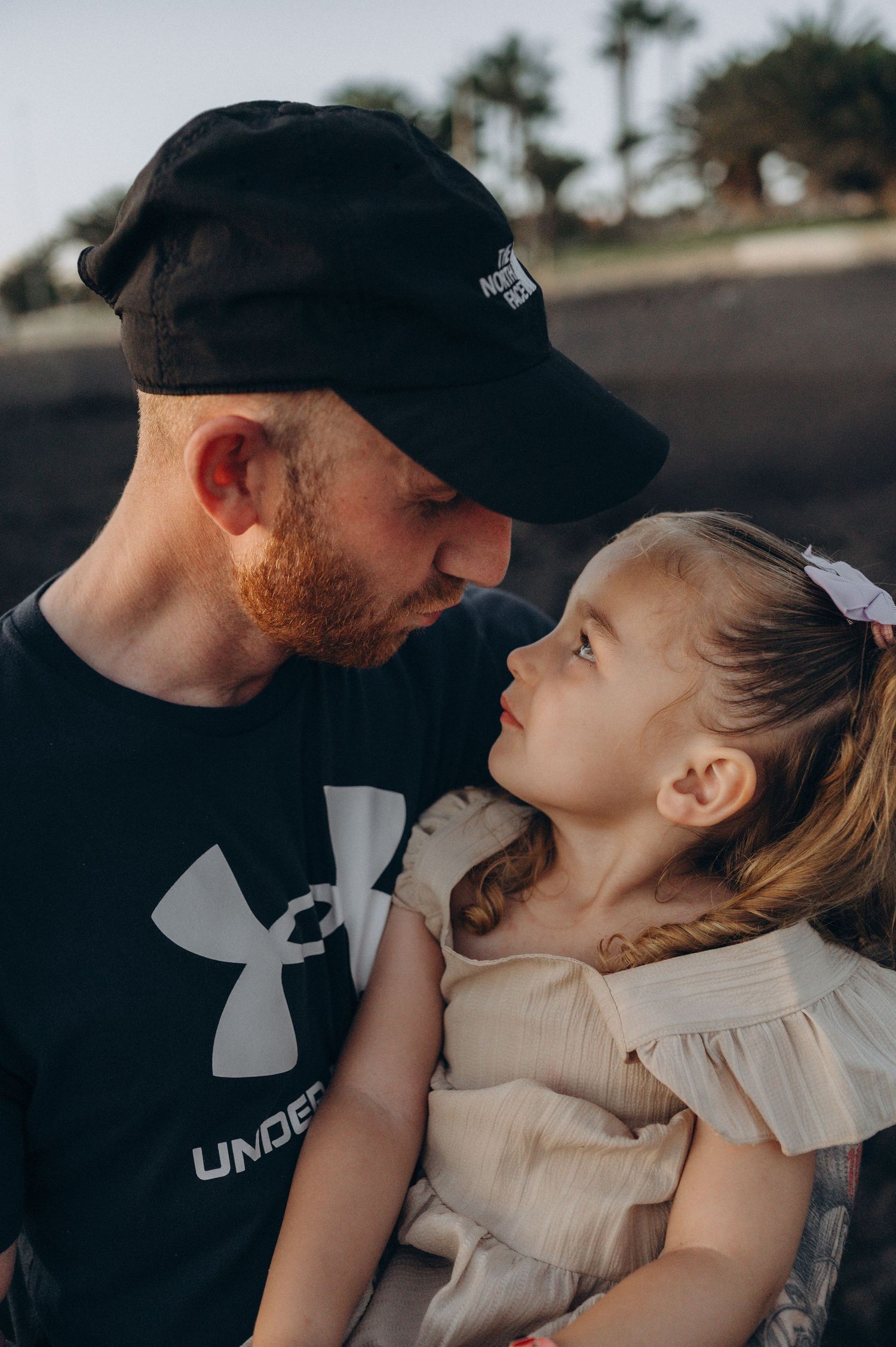 Tender father and daughter close up moment with tropical palm trees behind them in Tenerife