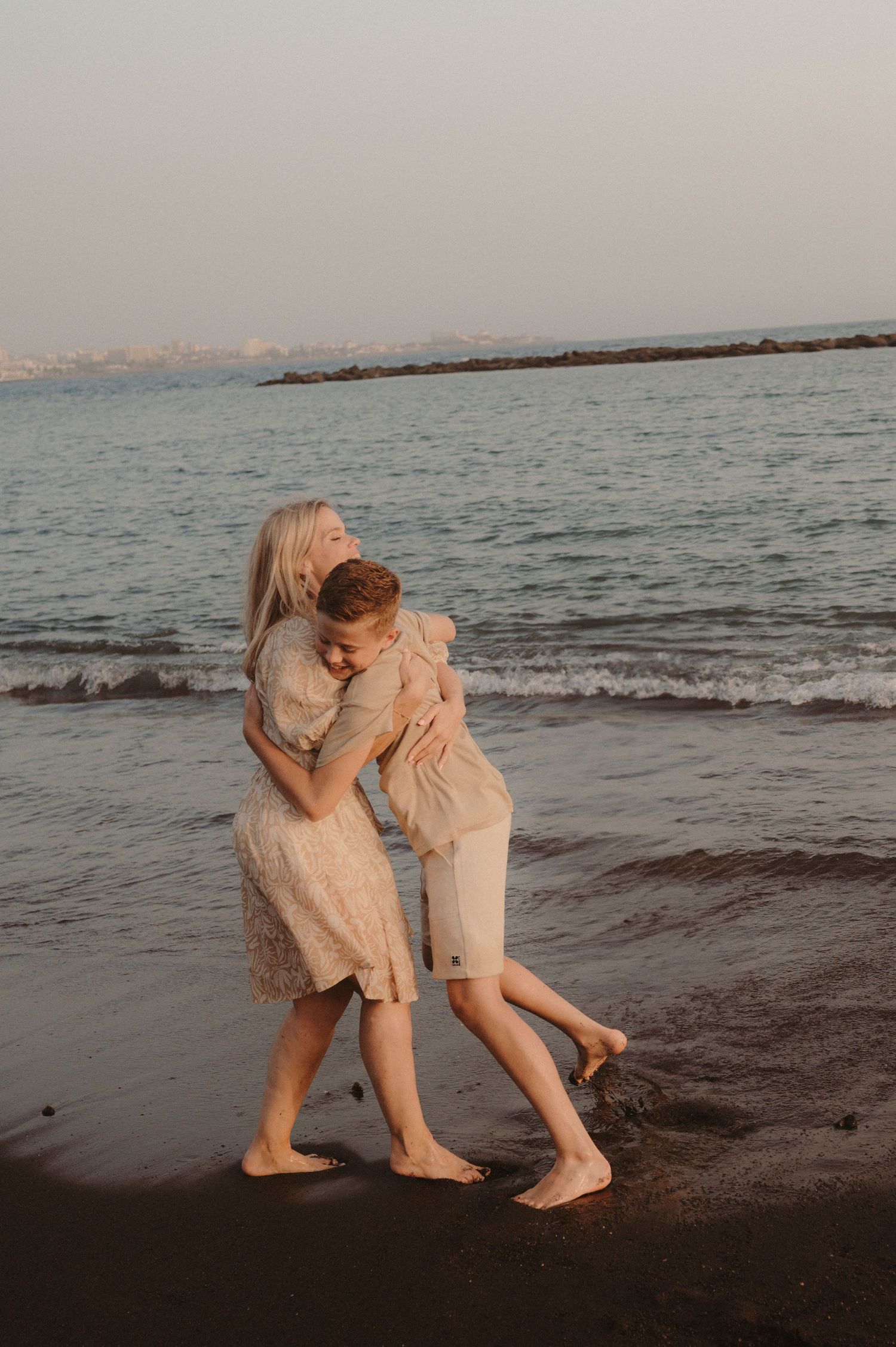 Mother hugging her son on beach at sunset, Playa del Duque