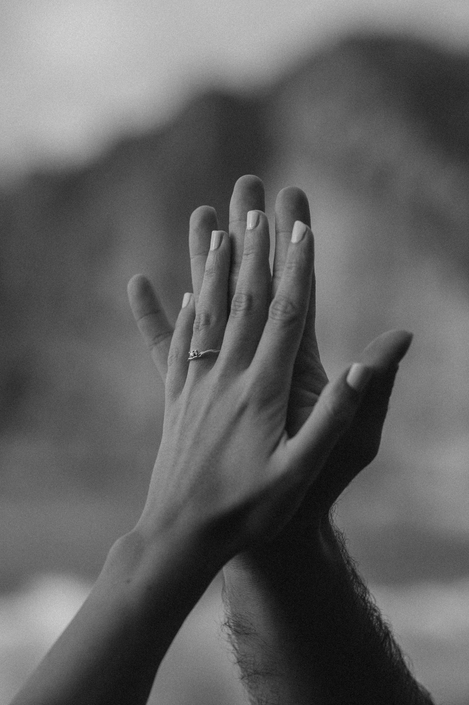 Close-up of joined hands of a couple on Playa de Los Guíos with cliffs in the background, Tenerife
