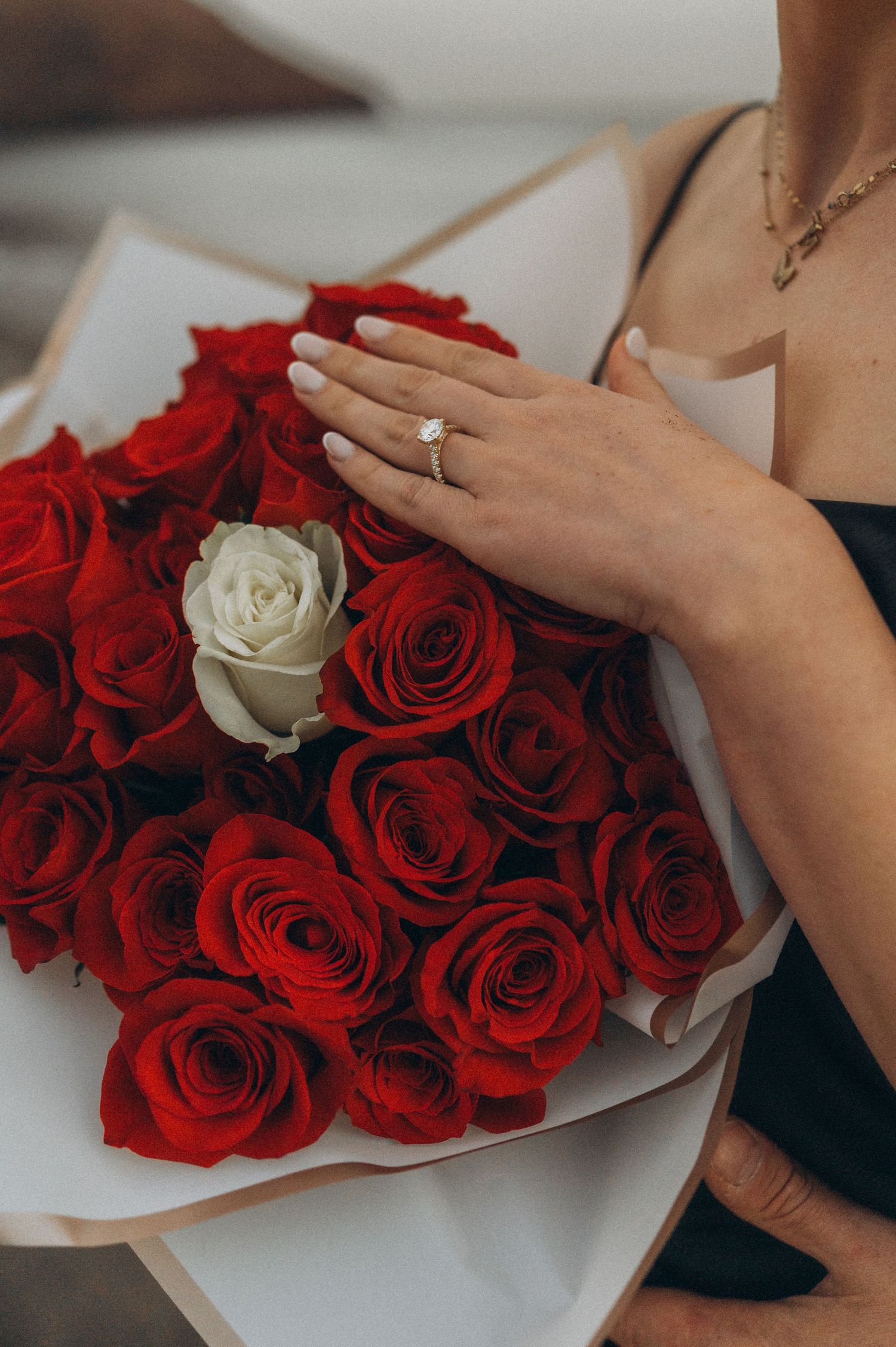 Close-up of engagement ring on hand resting on bouquet of red roses, Playa de La Tejita, Tenerife