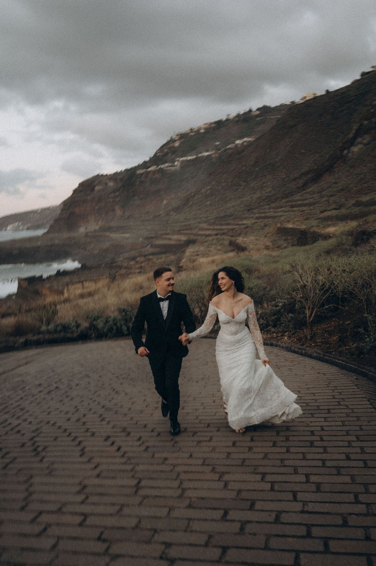 Wedding couple holding hands walking in elegant attire, Costa El Sauzal Tenerife