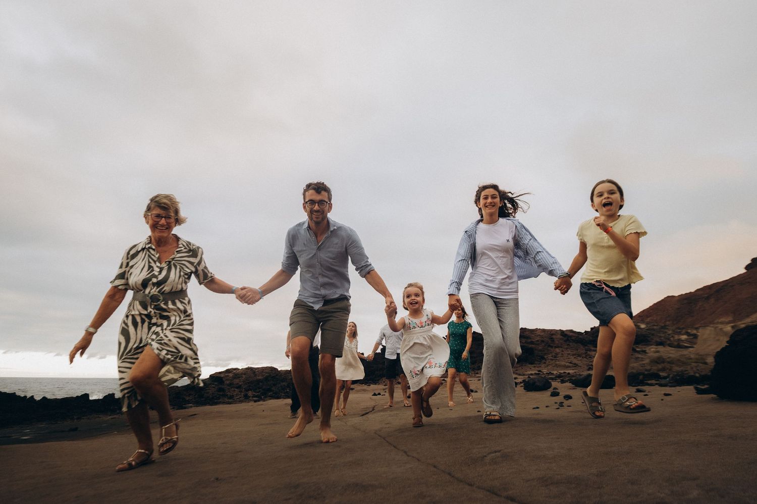 Candid moment of five family members running along Tenerife’s rocky shoreline