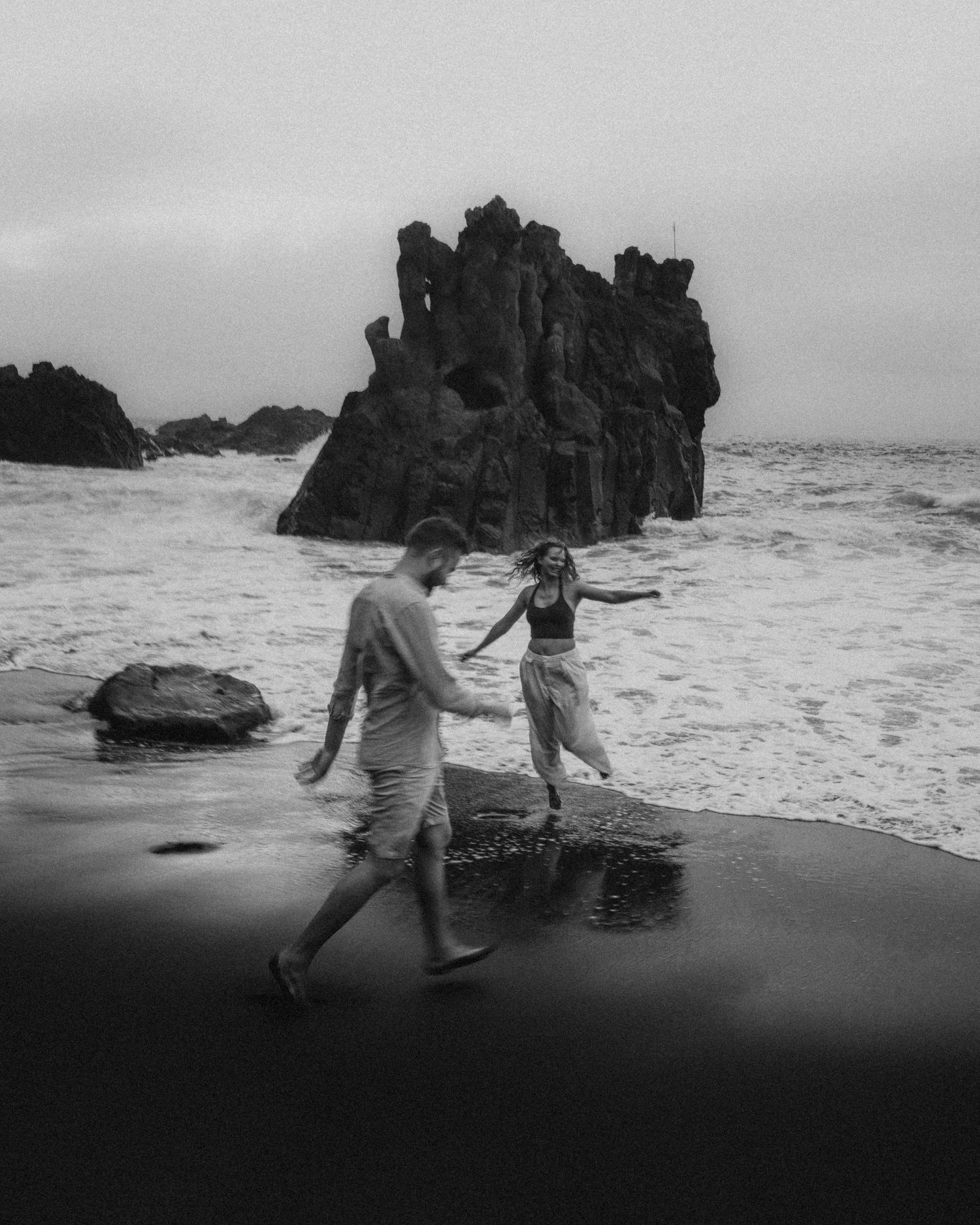 Young couple enjoying photoshoot on Playa Bollullo with ocean and cliffs, Tenerife