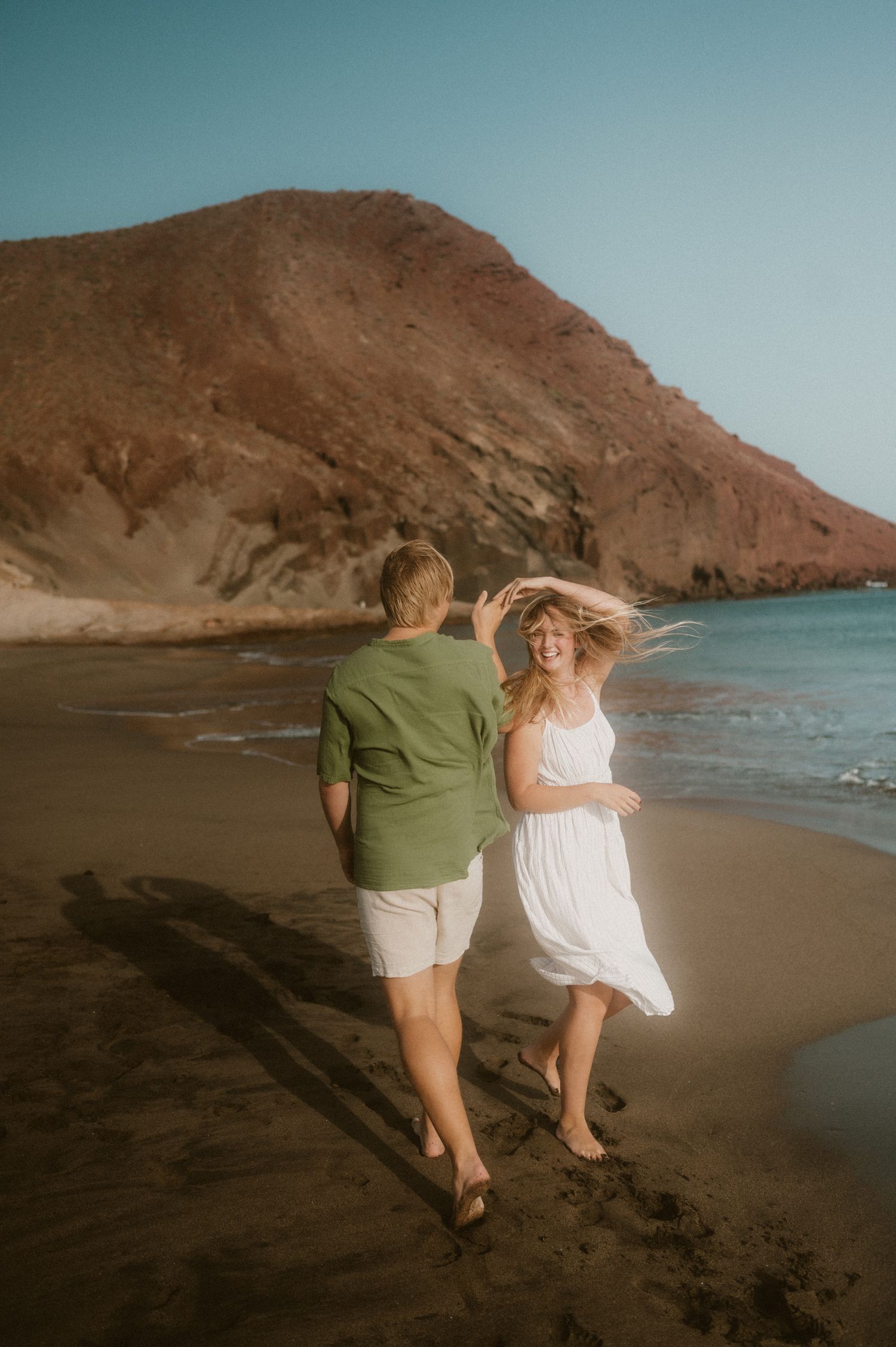 Young couple dancing barefoot on Playa Tejita, enjoying the sunset during a couples photoshoot, Tenerife