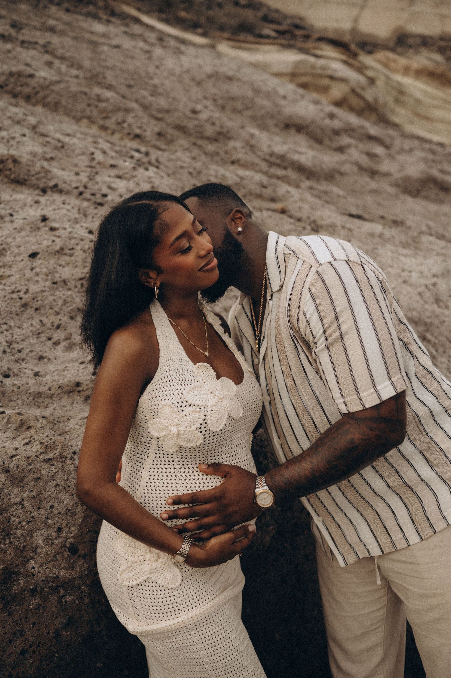 Romantic maternity moment with partner kissing neck and holding belly together