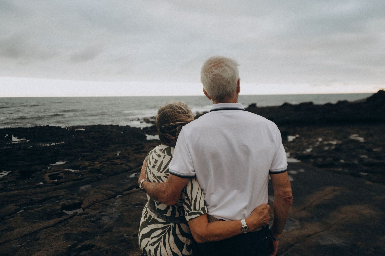 Elderly couple embracing from behind while looking at the endless Atlantic Ocean